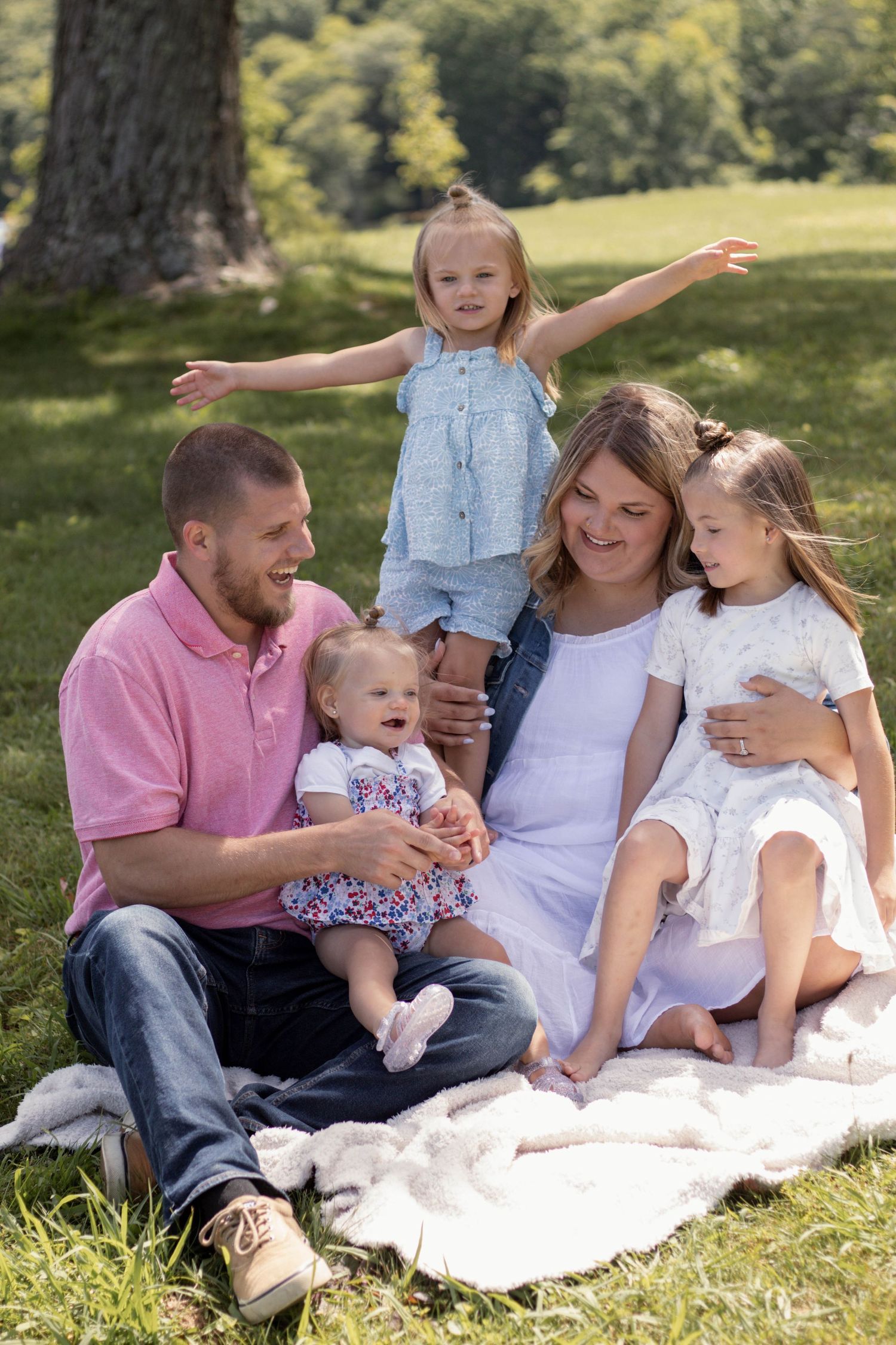 Family enjoying a picnic on a blanket in a sunny park.