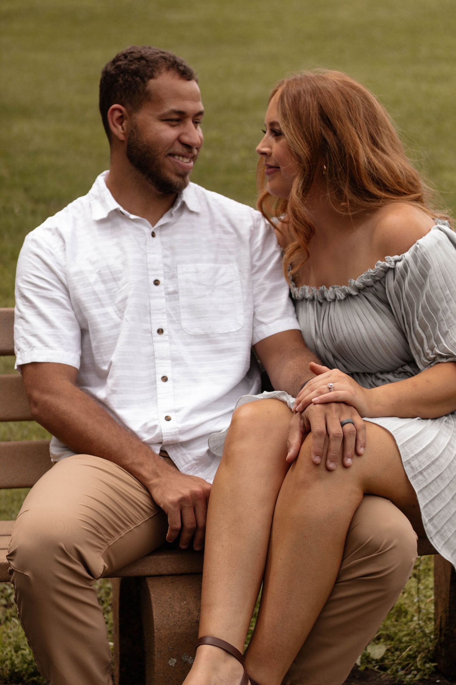 Couple sitting on bench sharing an intimate moment in casual summer outfits.