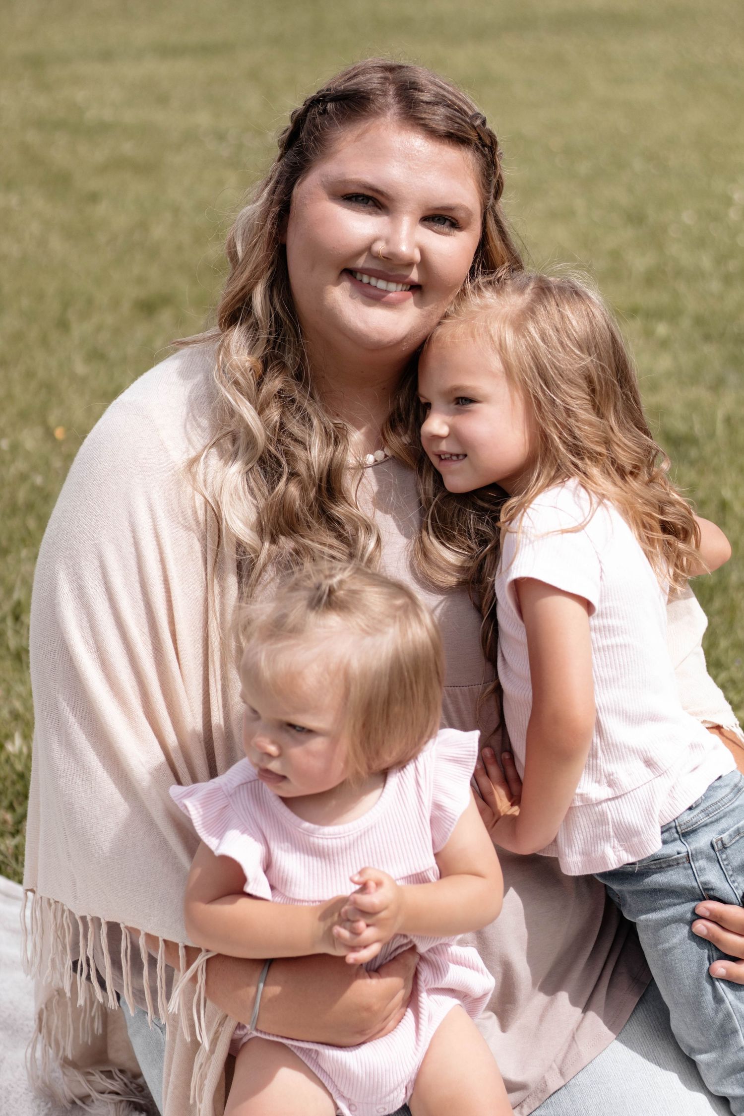 A tender family moment captured outdoors in natural sunlight.