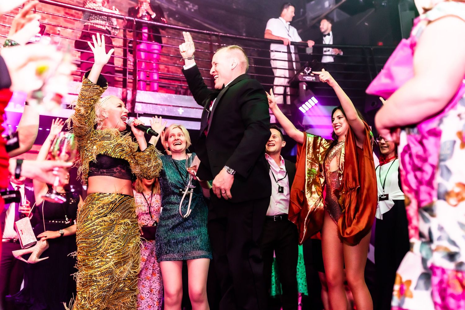 Festive crowd dancing and celebrating at a colorful party event with vibrant stage lighting.
Ministry of Sound London