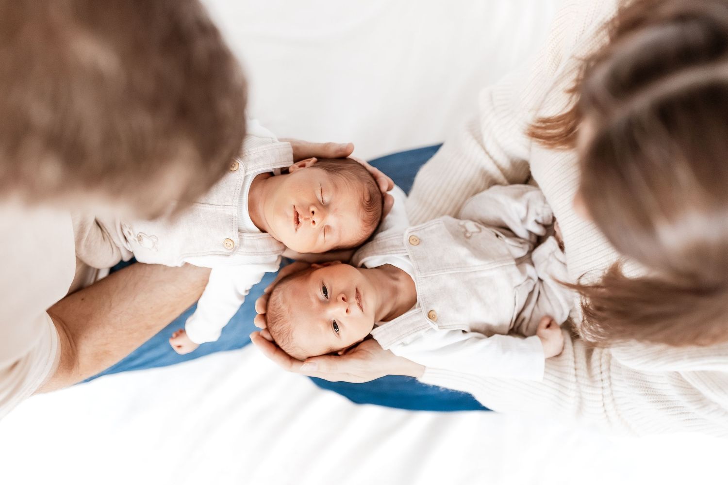 Artistic series of newborn twin photographs showing different angles and poses on white bedding.