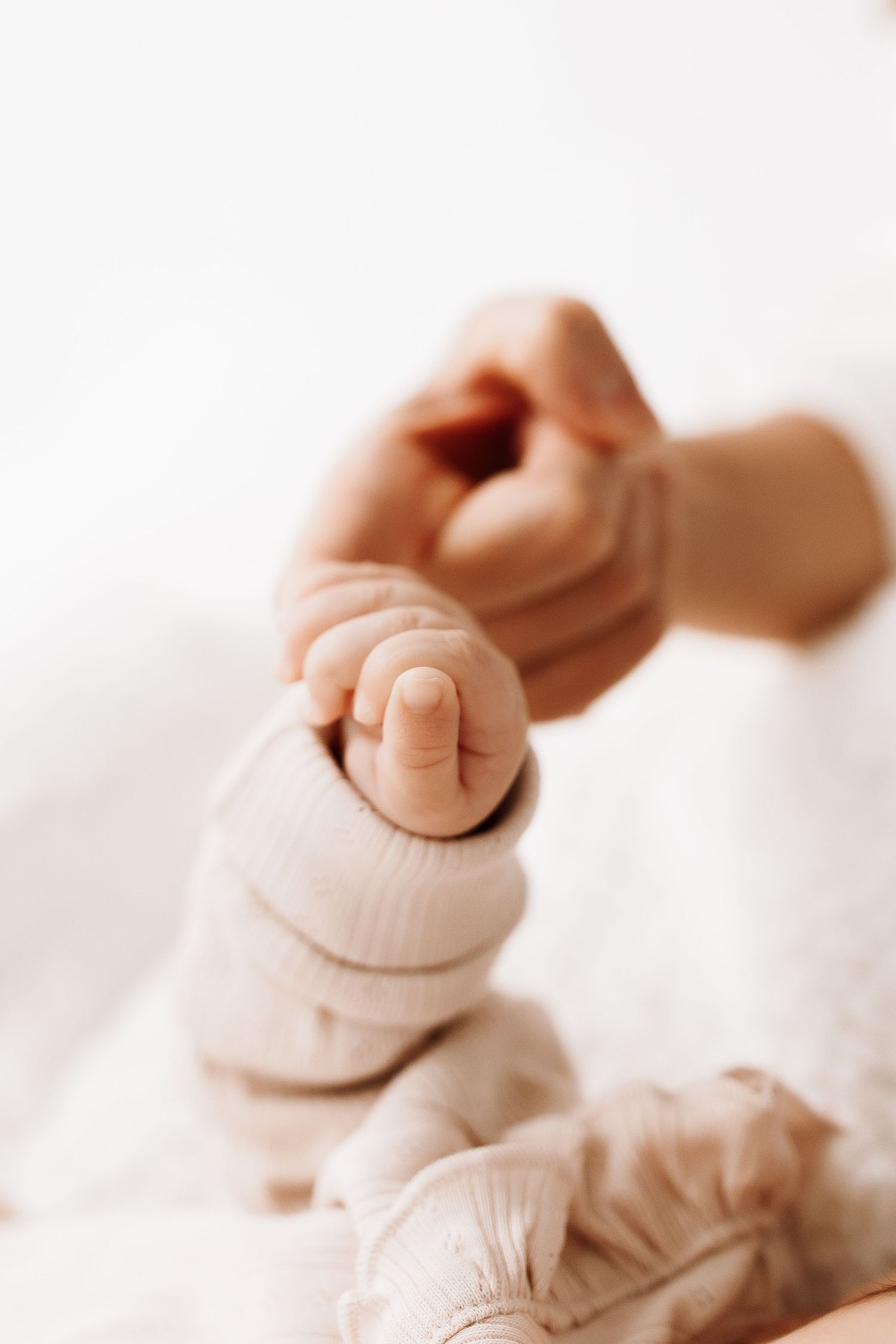 Close-up of tiny baby feet in soft focus with white background creating a tender newborn photography composition.