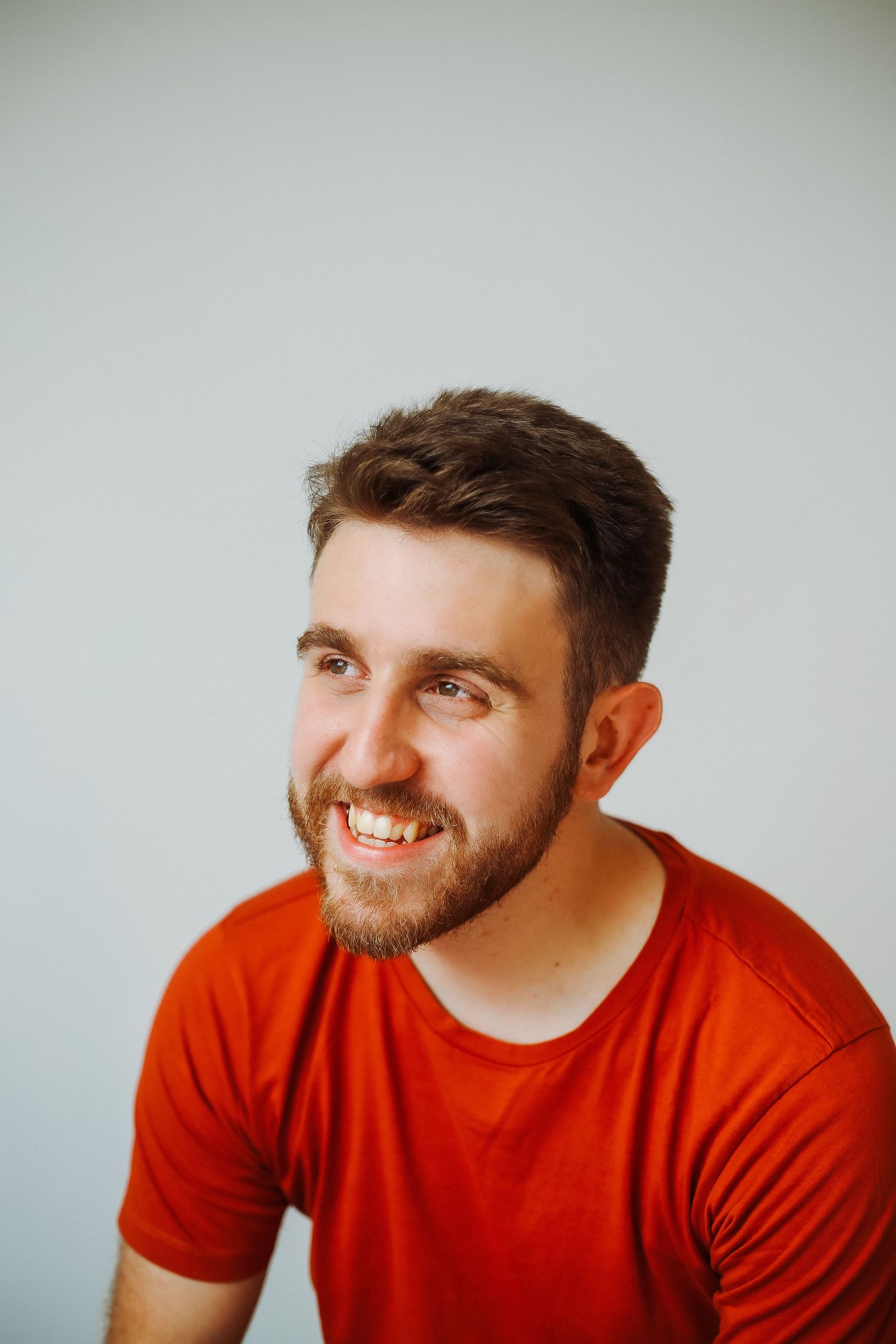 A series of five headshots showing a person in a red t-shirt expressing different emotions and poses against a light background.
