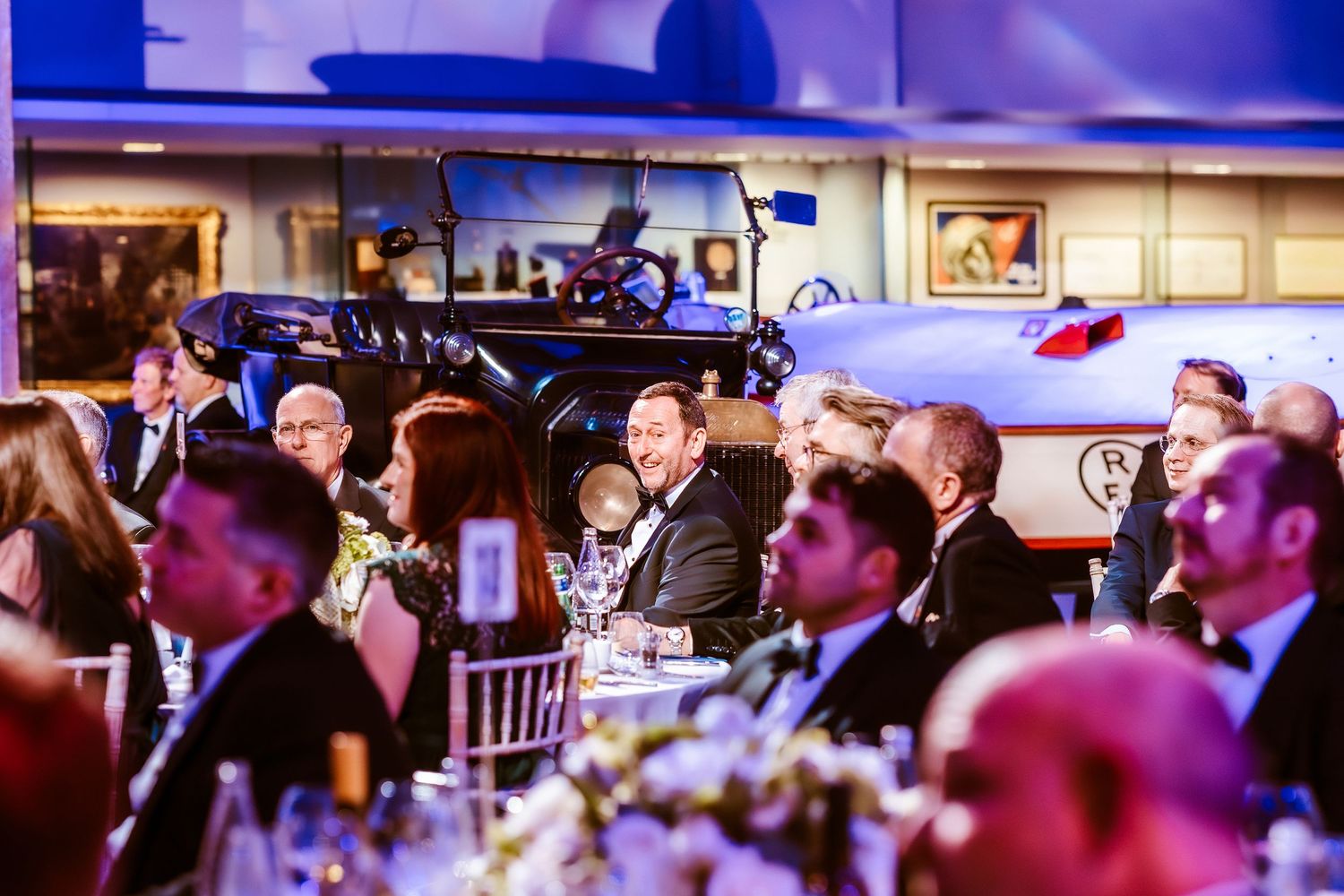 The Science Museum event Guests in formal attire seated at elegant banquet tables during a gala dinner event with a vintage train backdrop.