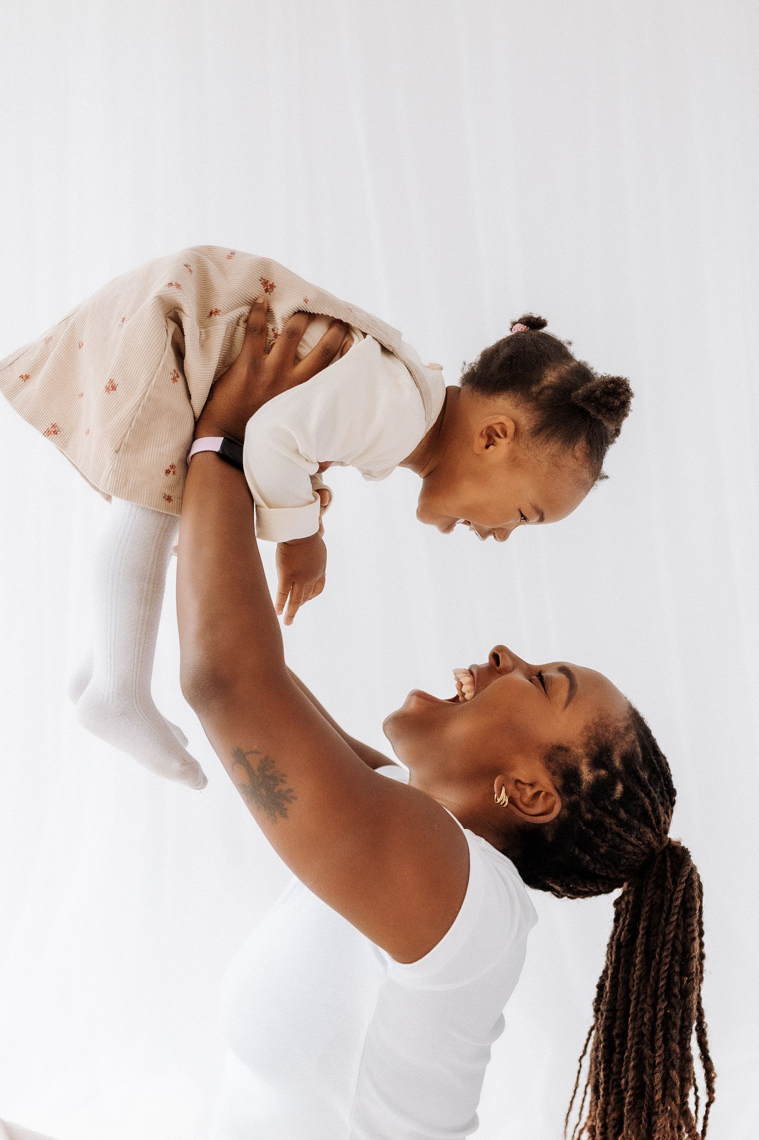 A joyful parent lifts a baby wearing white clothes against a bright background in a series of connected photos.