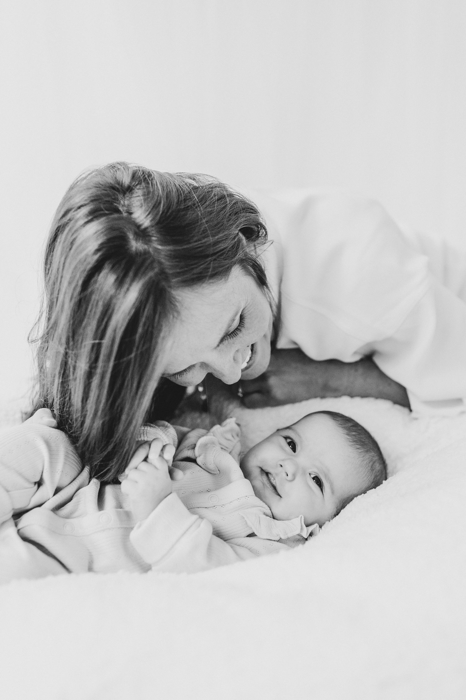 Parent and baby laughing together against a minimalist white background. candid photography baby, family Shepperton Surrey studio