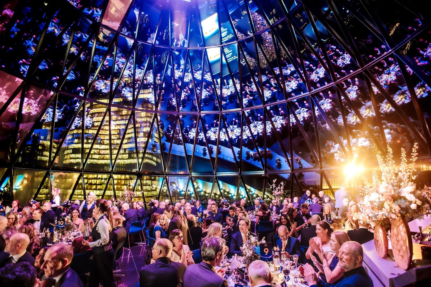 The Gherkin London, Elegant gala dinner event in a stunning venue with dramatic blue lighting, floral arrangement