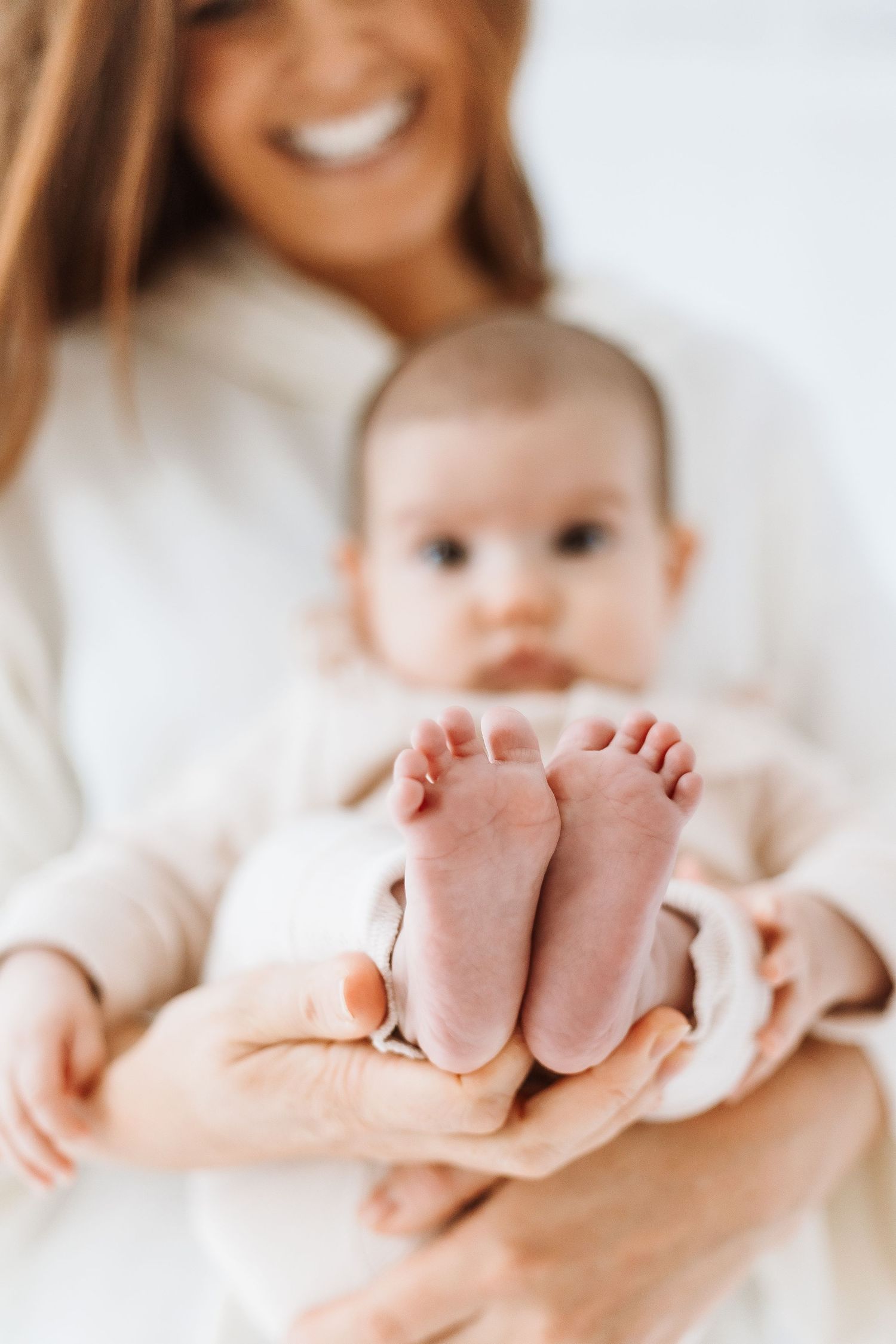 Close-up series of tiny baby feet being held gently in adult hands wearing white knit sweater.