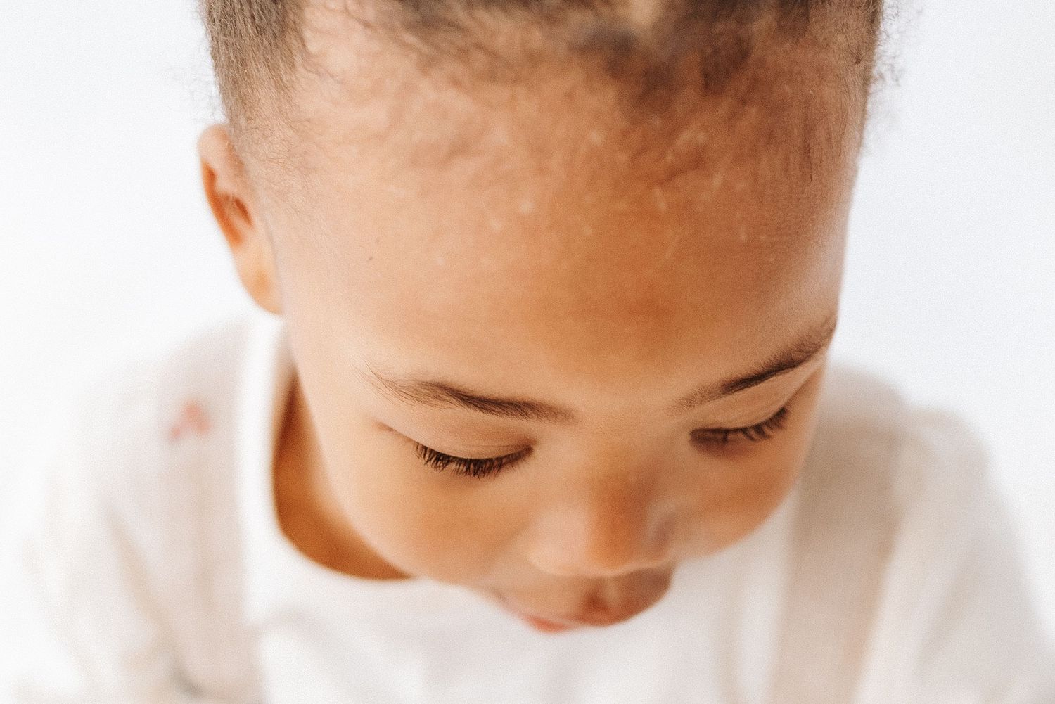 Shepperton Surrey photography studio. Close-up portrait of a young child looking down while wearing a white shirt in soft natural lighting.