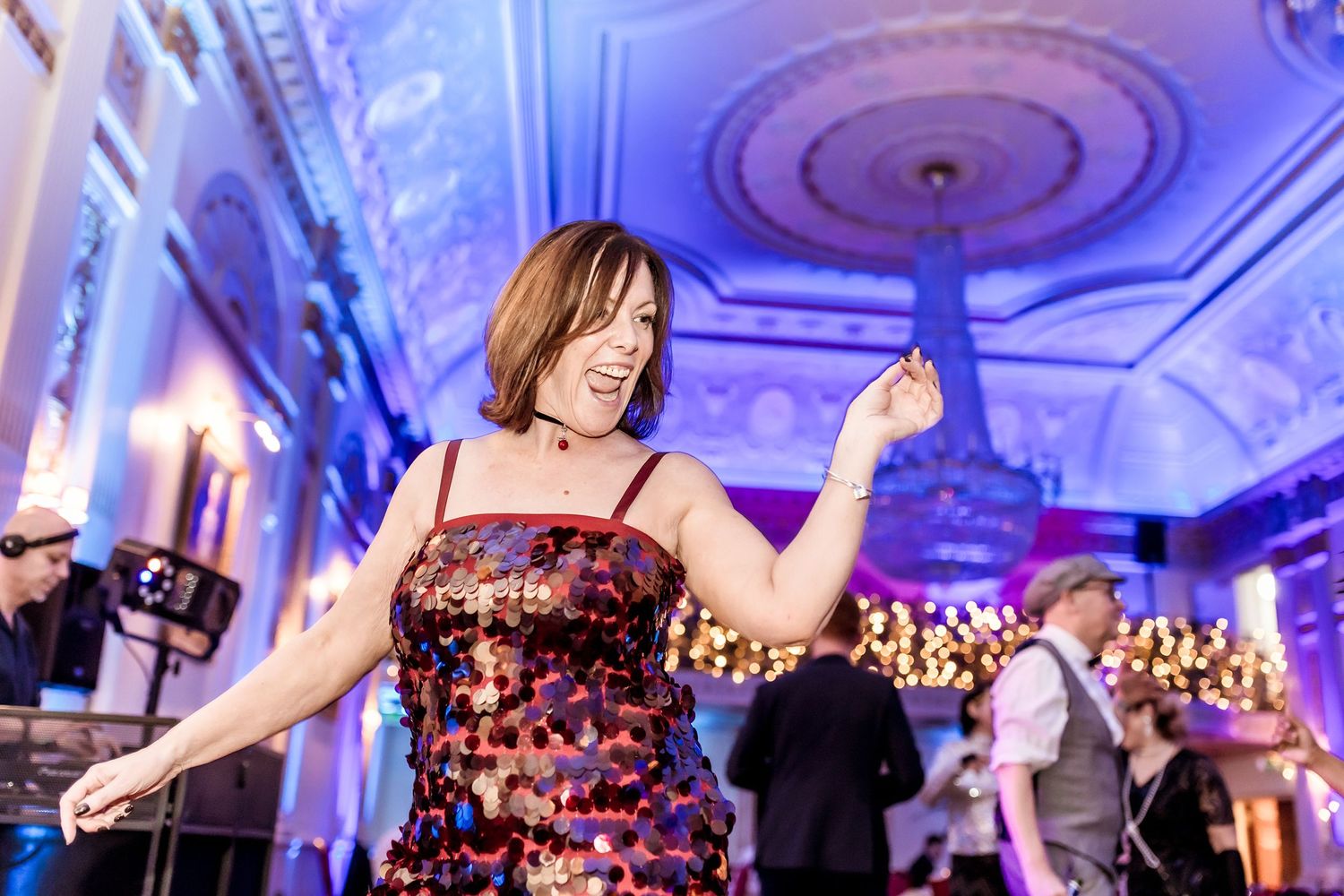 Event at the plaisterers hall Woman in sequined dress dancing at elegant ballroom event with blue lighting and live band.