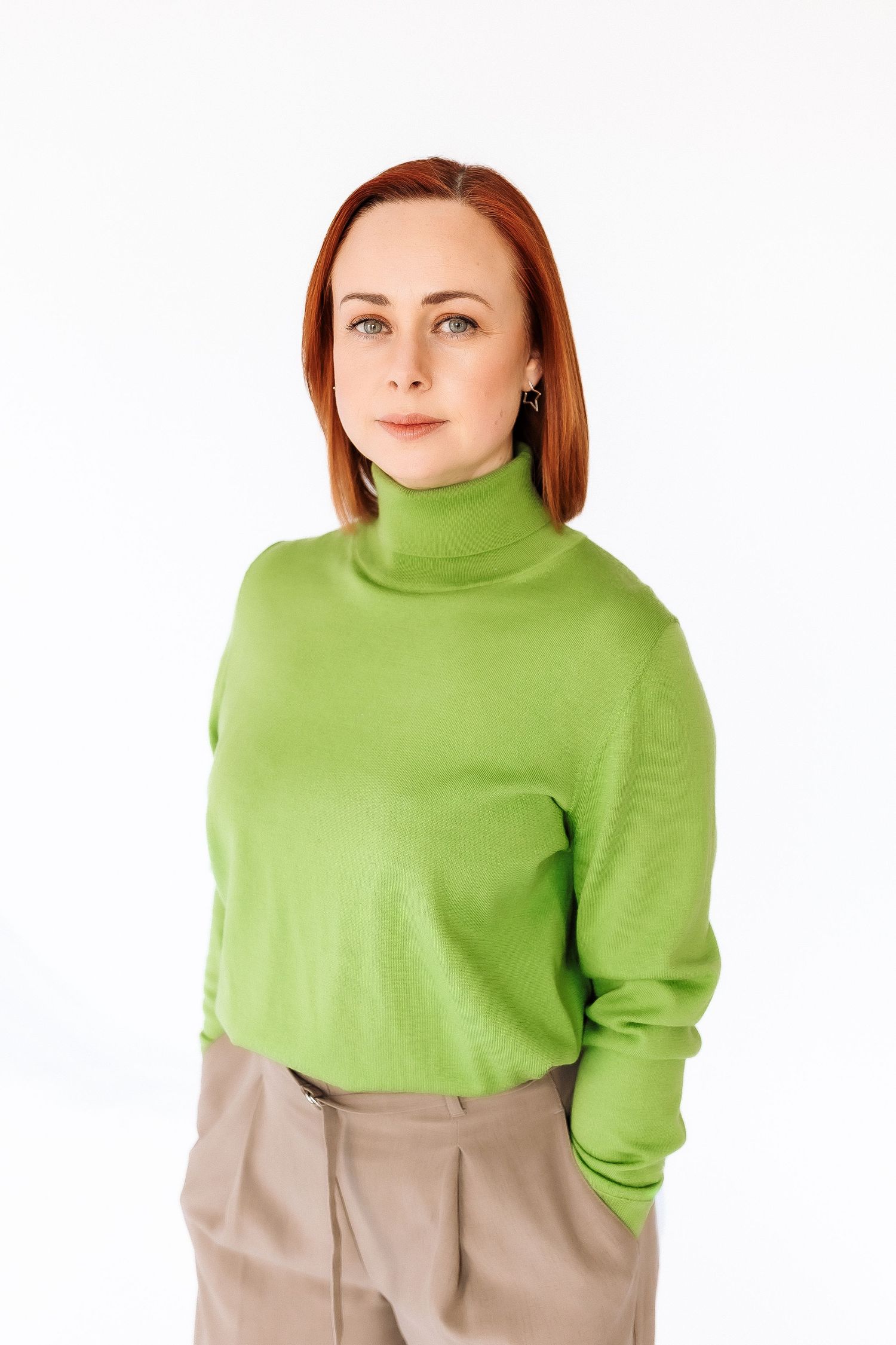 A person wearing a bright lime green turtleneck sweater and beige pants poses in three different positions.