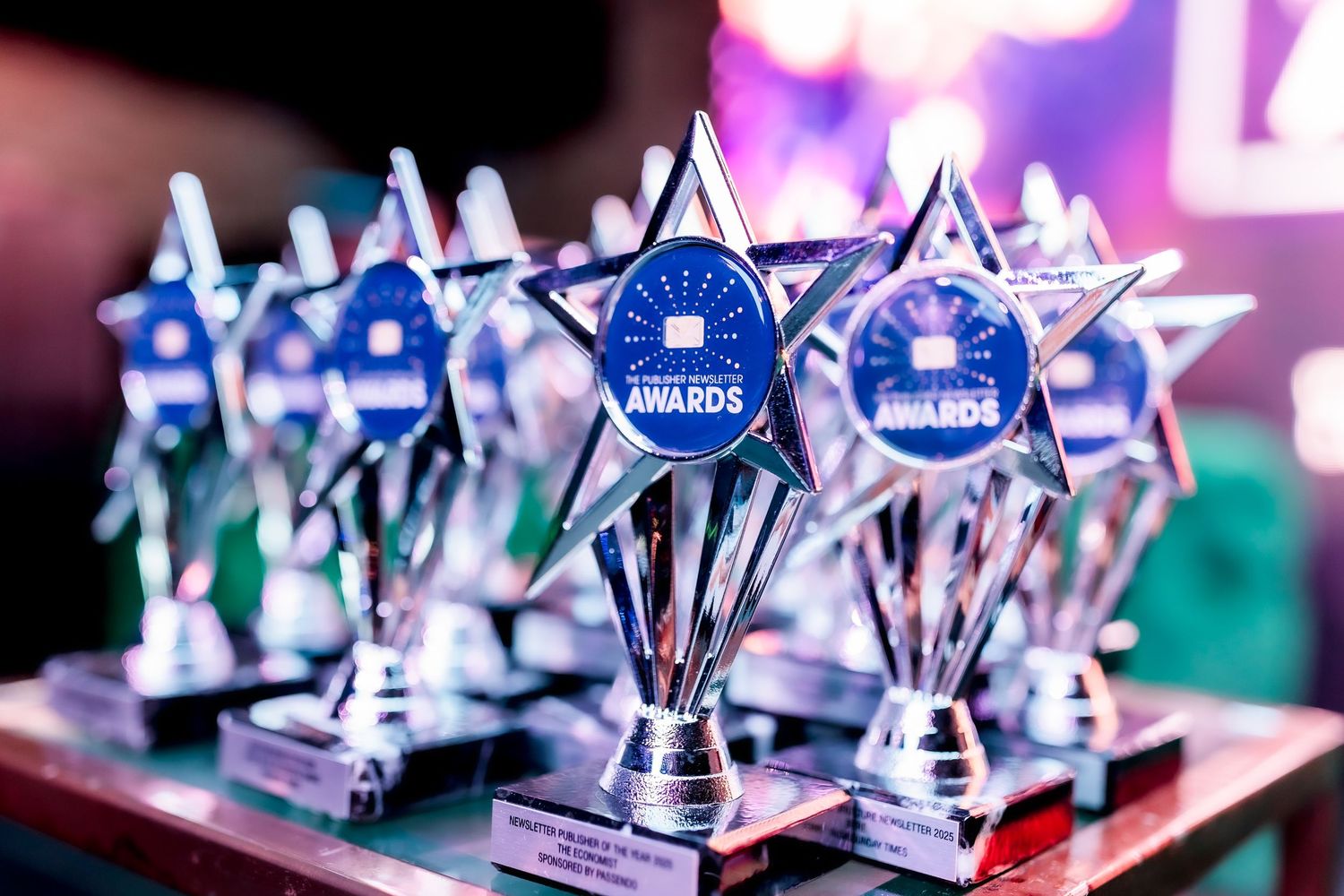 Award ceremony for podcast awardsMultiple shiny star-shaped awards trophies with blue medallions displayed on a table at an awards ceremony.