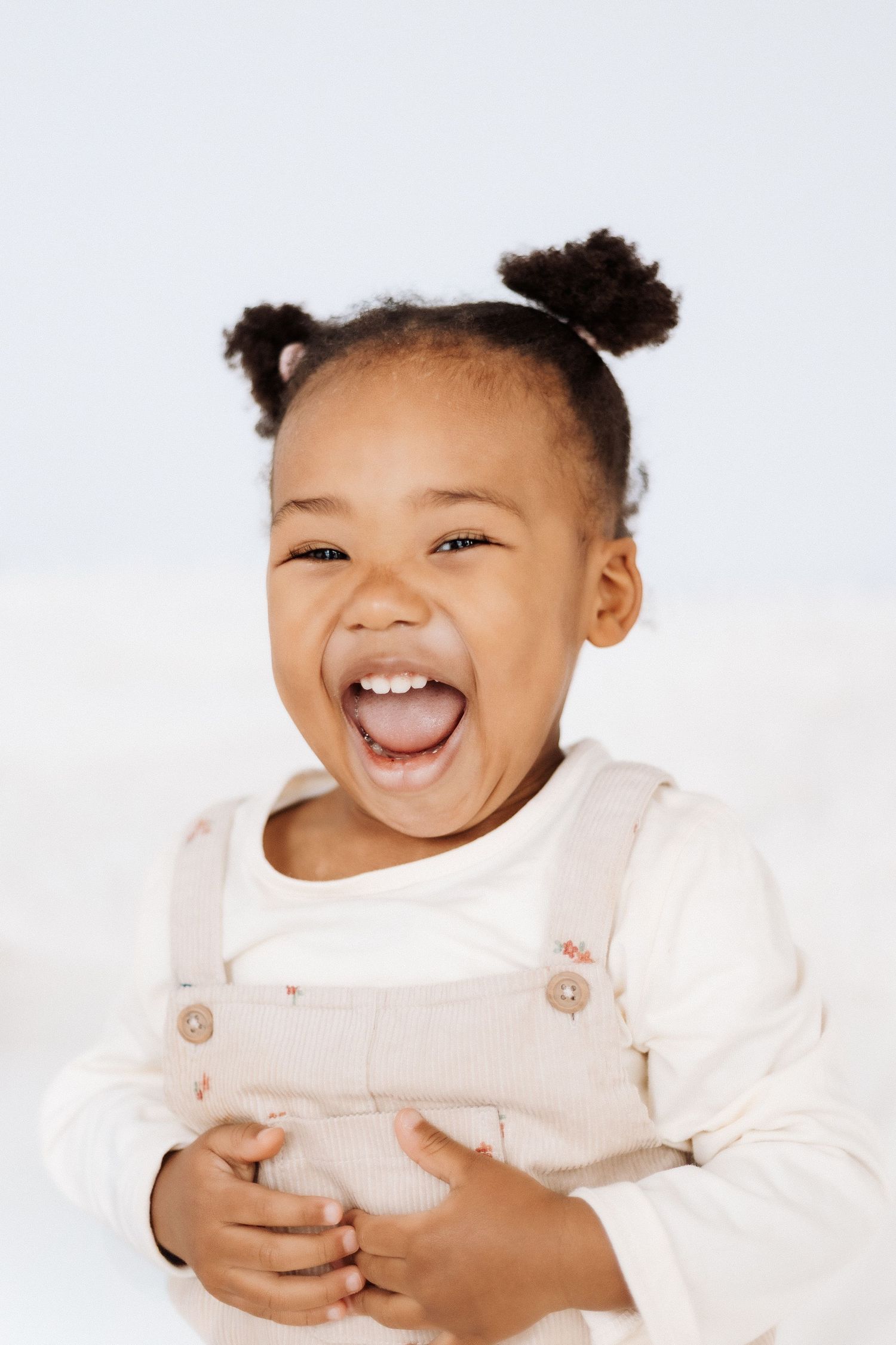 pure delight and laughter against white backdrop. Shepperton Surrey photography studio portrait baby child session natural lighting.