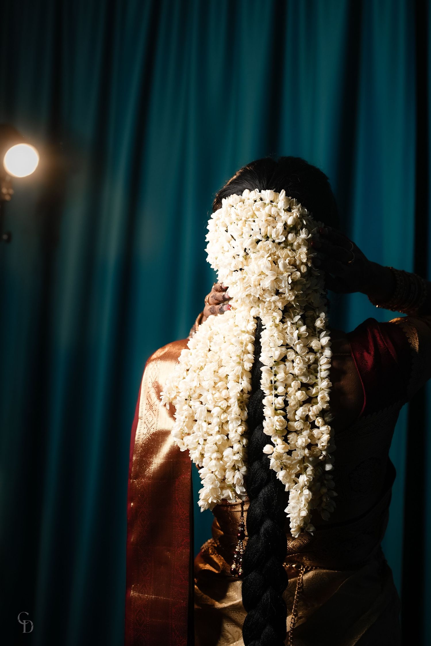 Beautiful white jasmine flower garland cascades down in dramatic lighting against turquoise curtain backdrop.