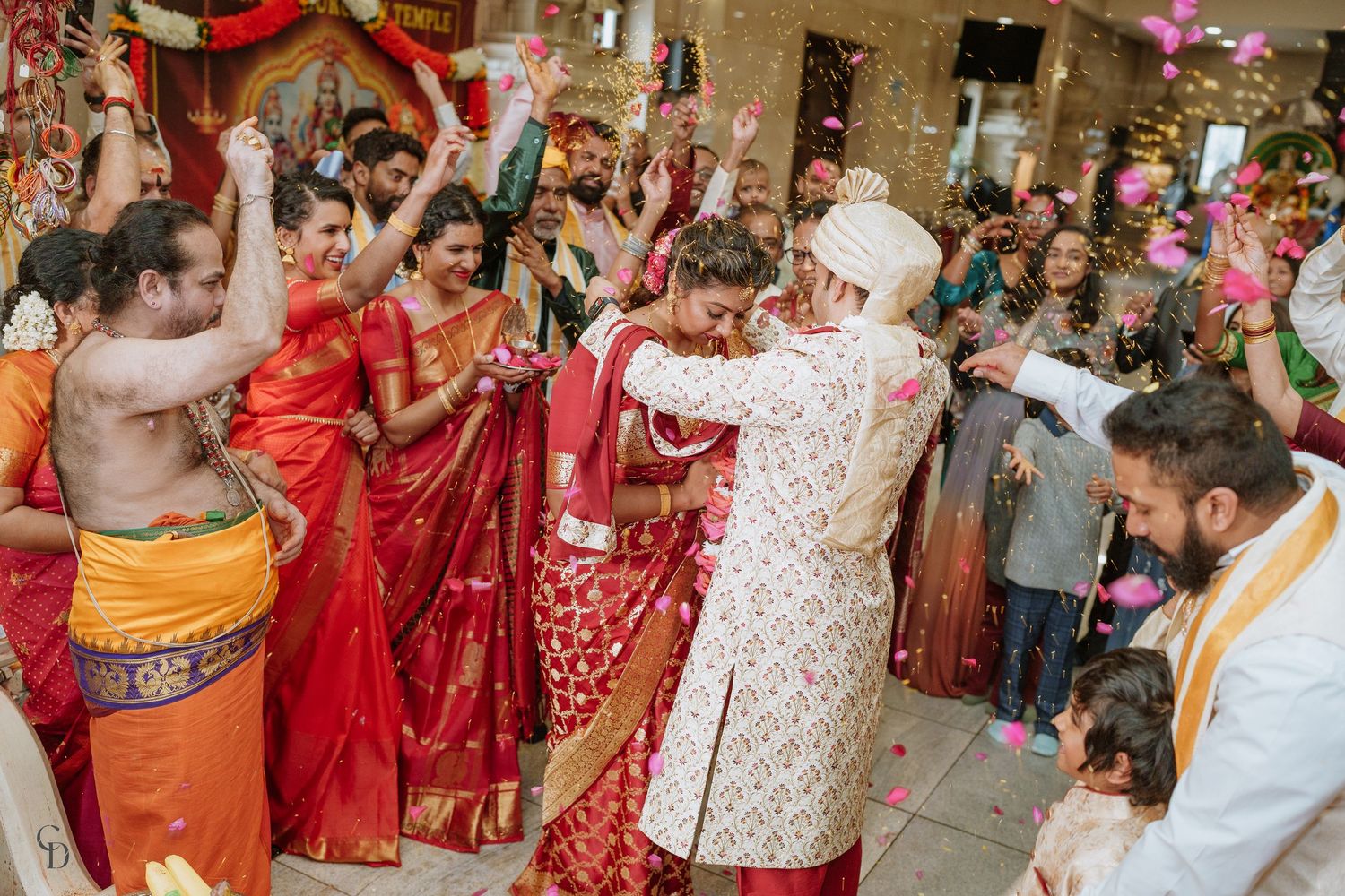 Festive wedding celebration with crowd in traditional Indian attire dancing and celebrating.