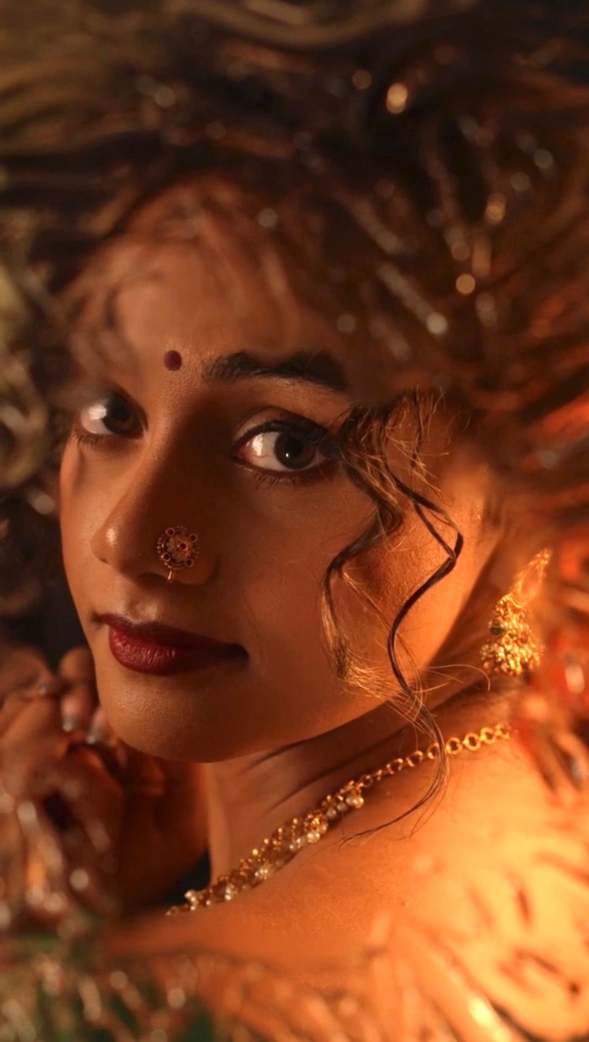 Artistic portrait with warm lighting showcasing traditional Indian bridal jewelry and makeup.