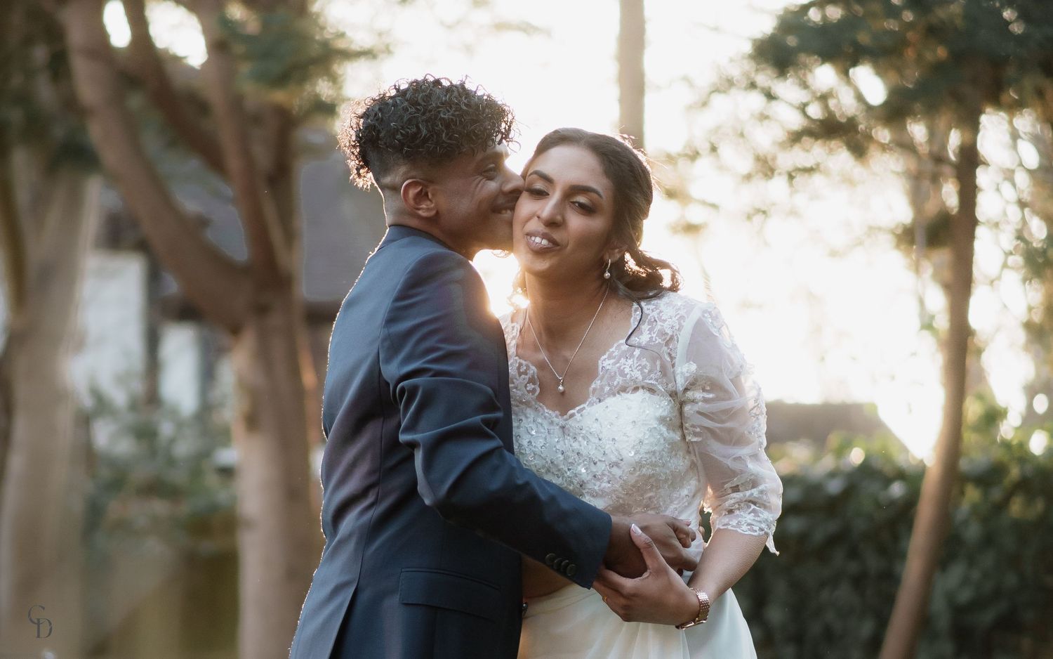Romantic wedding portrait captured during golden hour with elegant lace dress and intimate embrace.