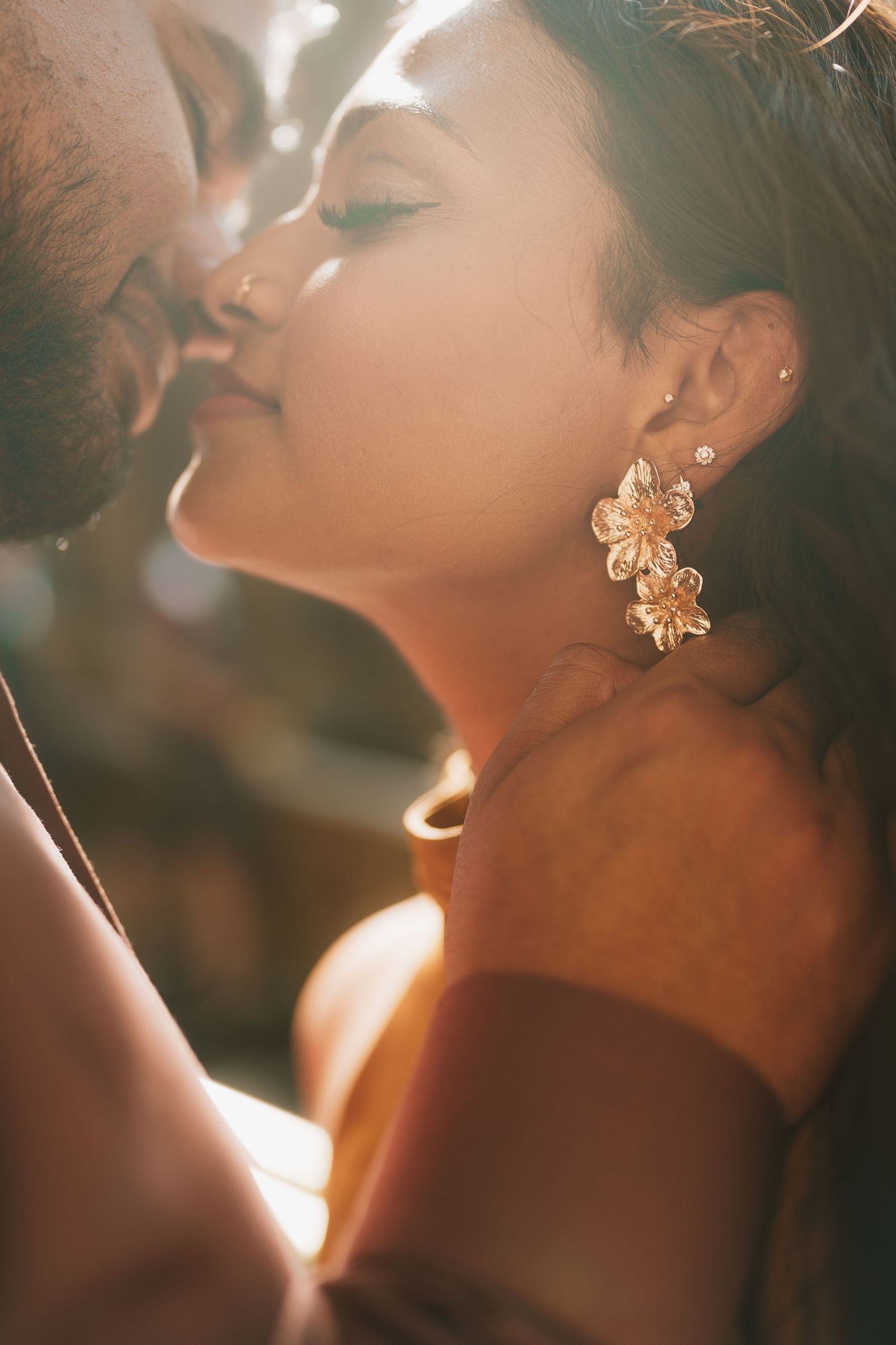Sun-illuminated artistic portrait taken in a warm light with flower-shaped stud earrings creating an ethereal atmosphere.