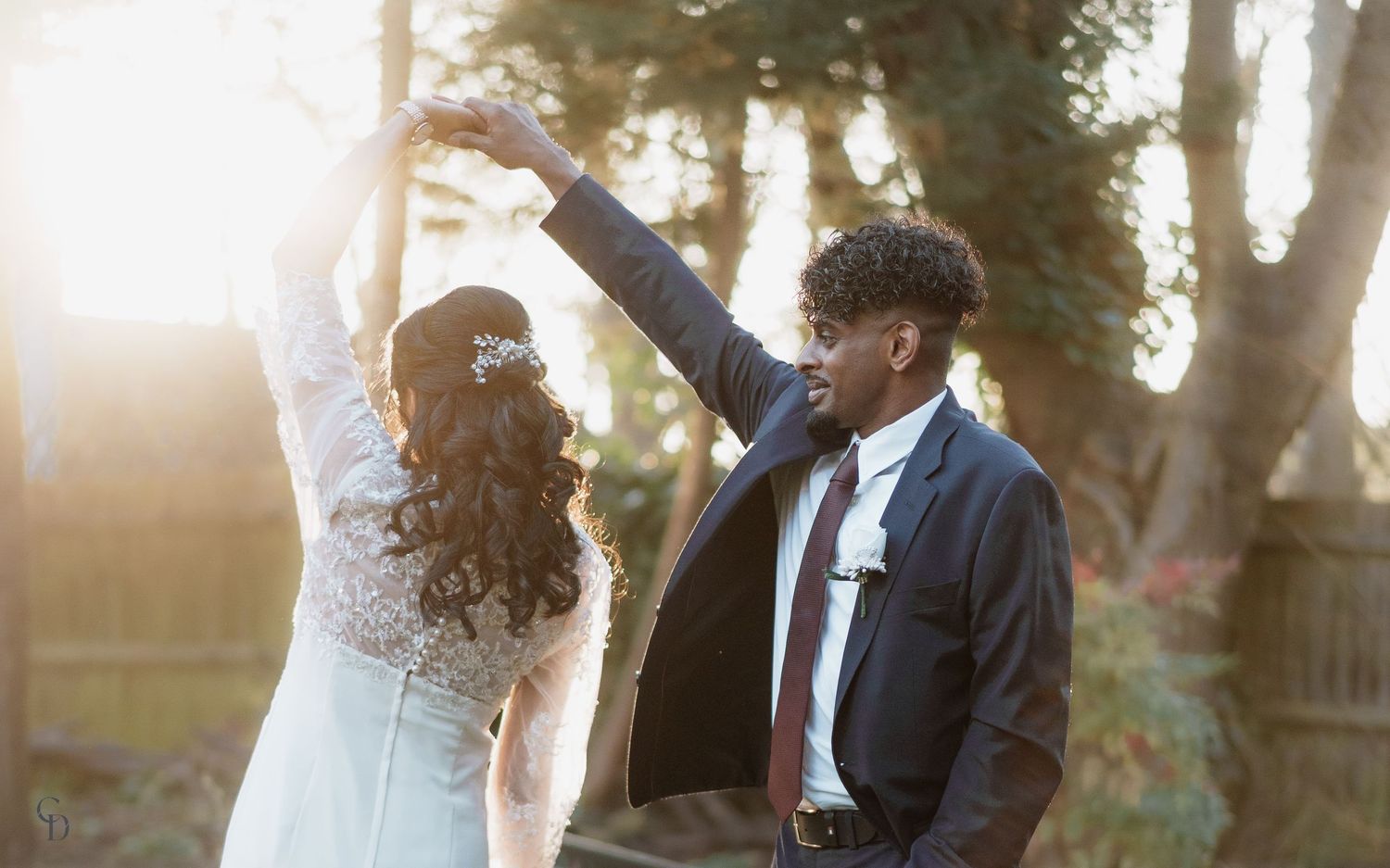 Romantic dancing moment between newlyweds in sunlit garden setting.