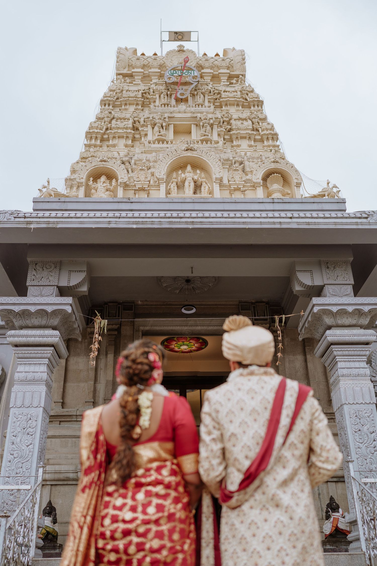 Traditional Indian couple admiring ornate Gopuram architecture at Hindu temple entrance.