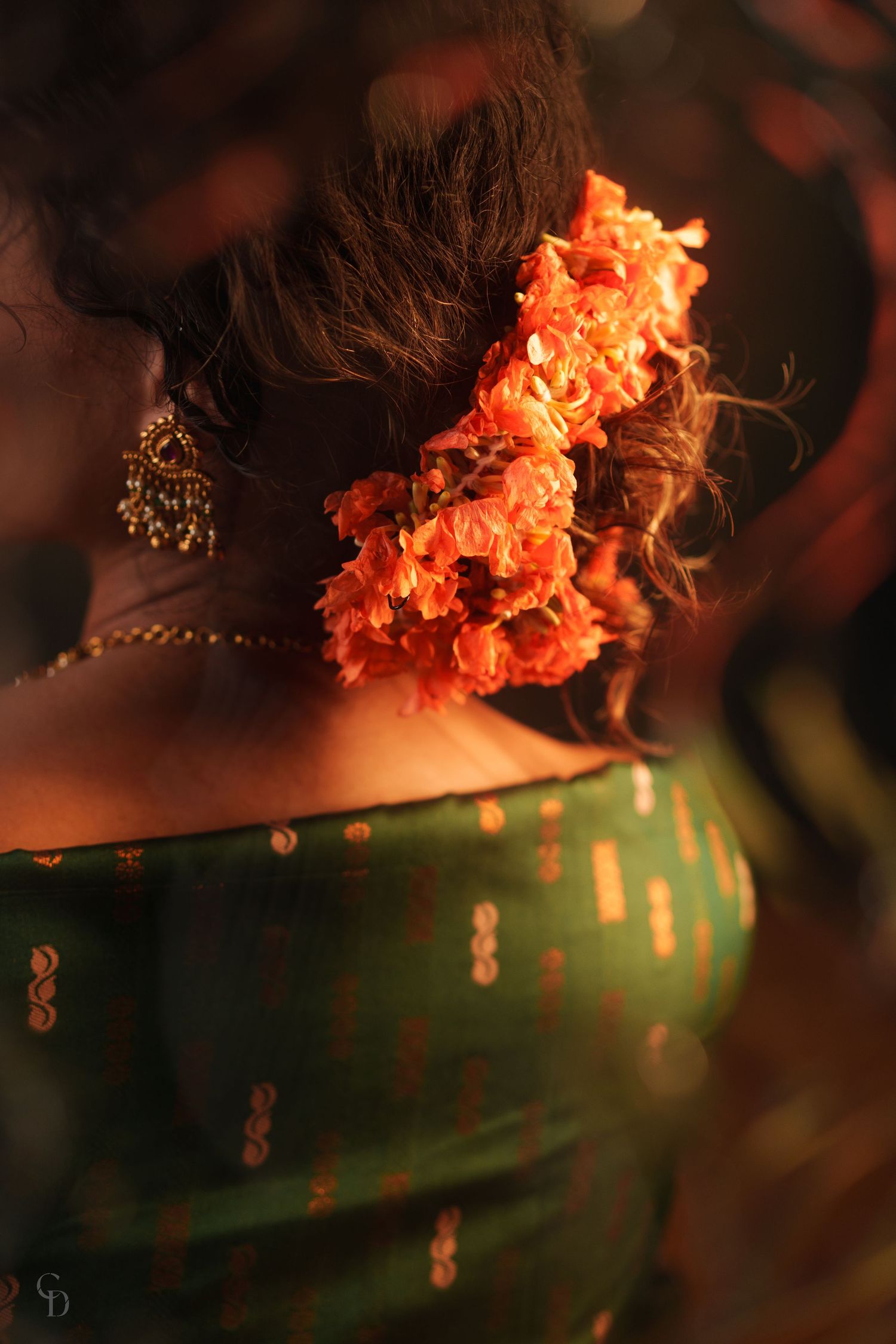 Orange flowers and traditional green sari fabric captured in moody lighting.