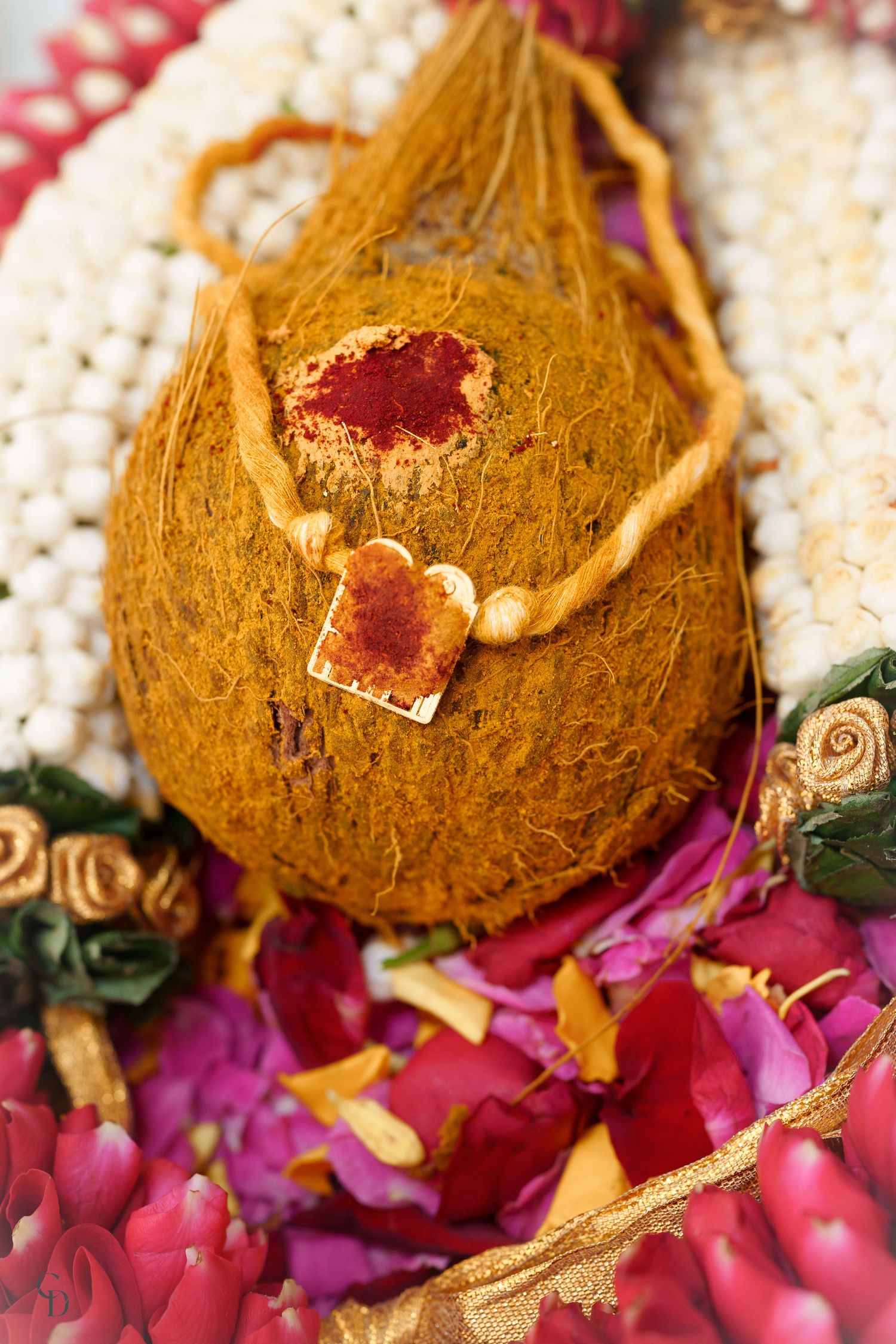 Decorated coconut with red kumkum and flowers for Indian wedding ceremony.