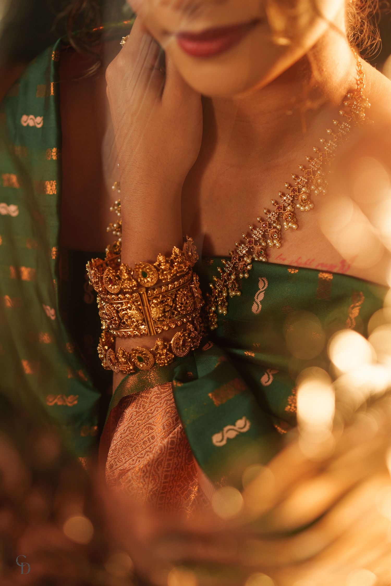 Intricate gold jewelry and embellishments adorning traditional Indian attire in warm lighting.