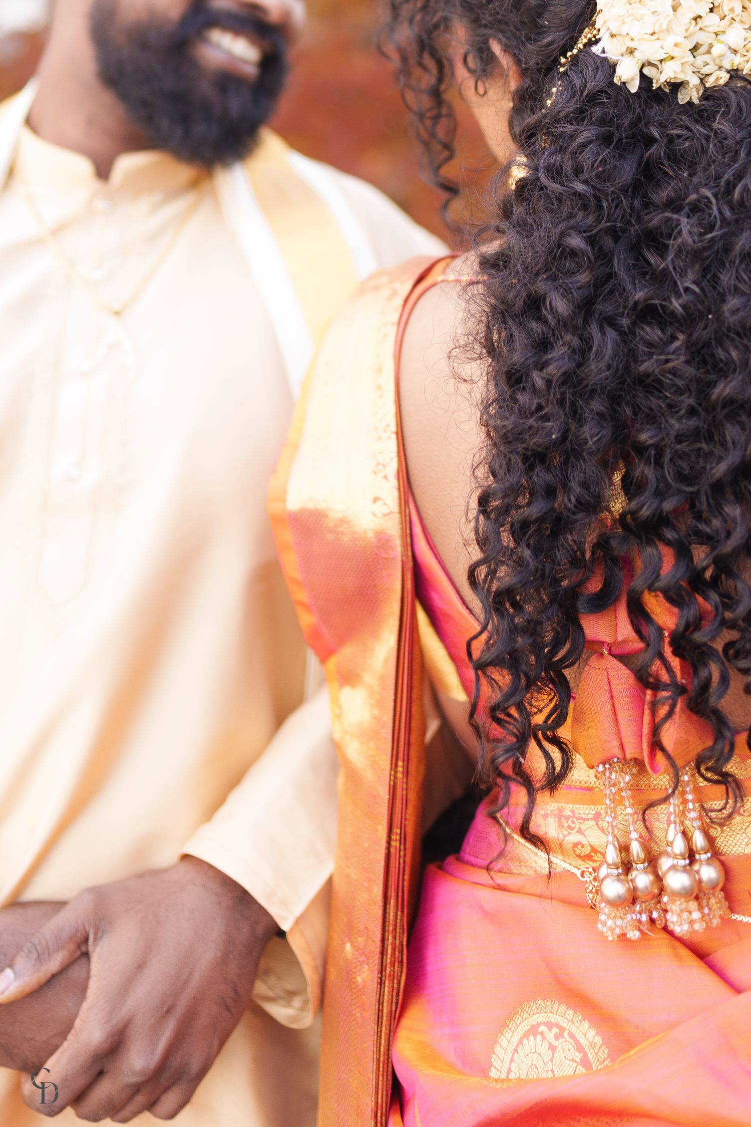 A close-up of intricately detailed traditional Indian wedding attire with curly hair and jewelry details.