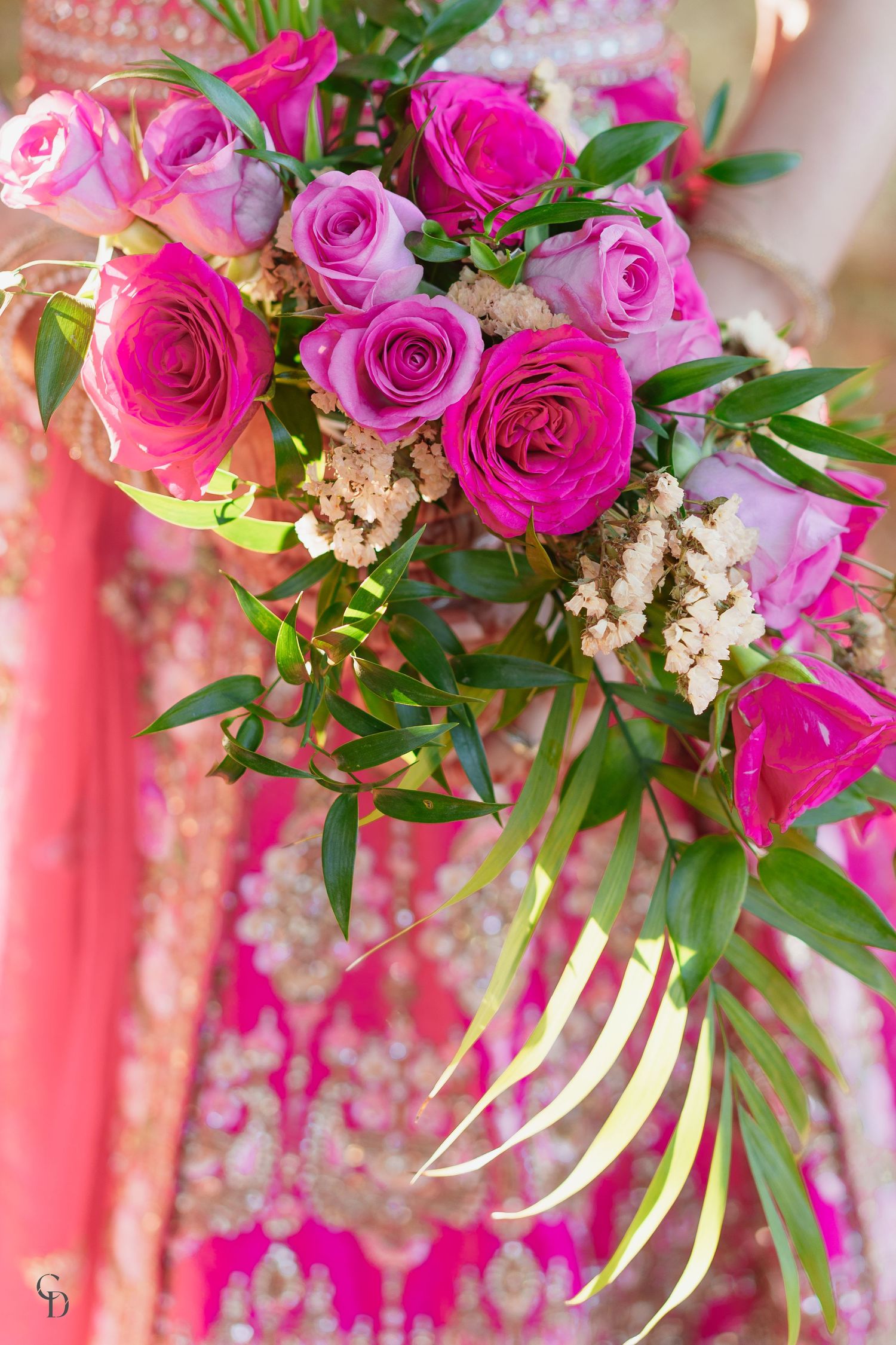 Vibrant pink and fuchsia roses arranged with greenery in a wedding bouquet.