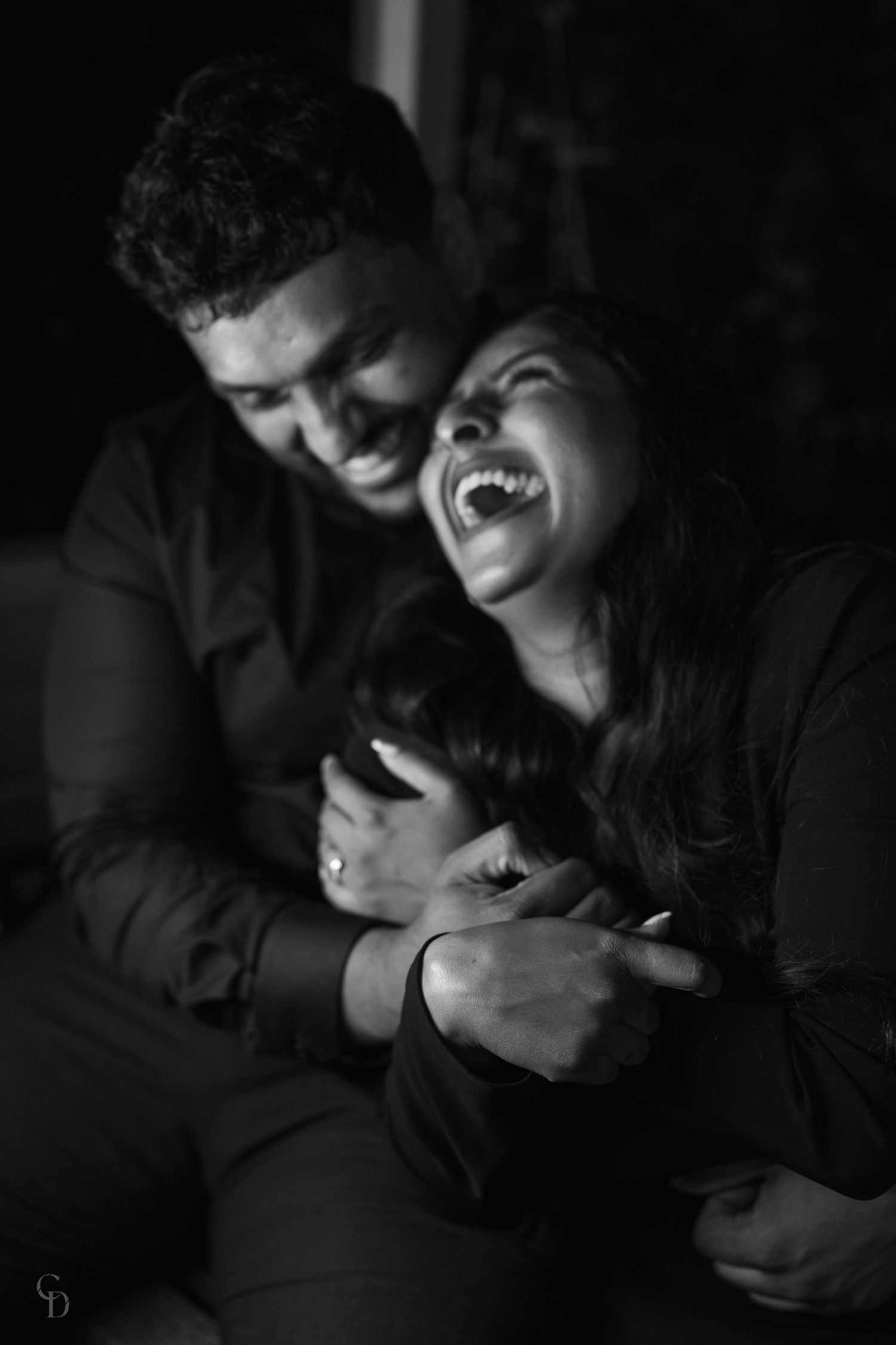 Candid black and white photo capturing a joyful laughing moment between a couple.