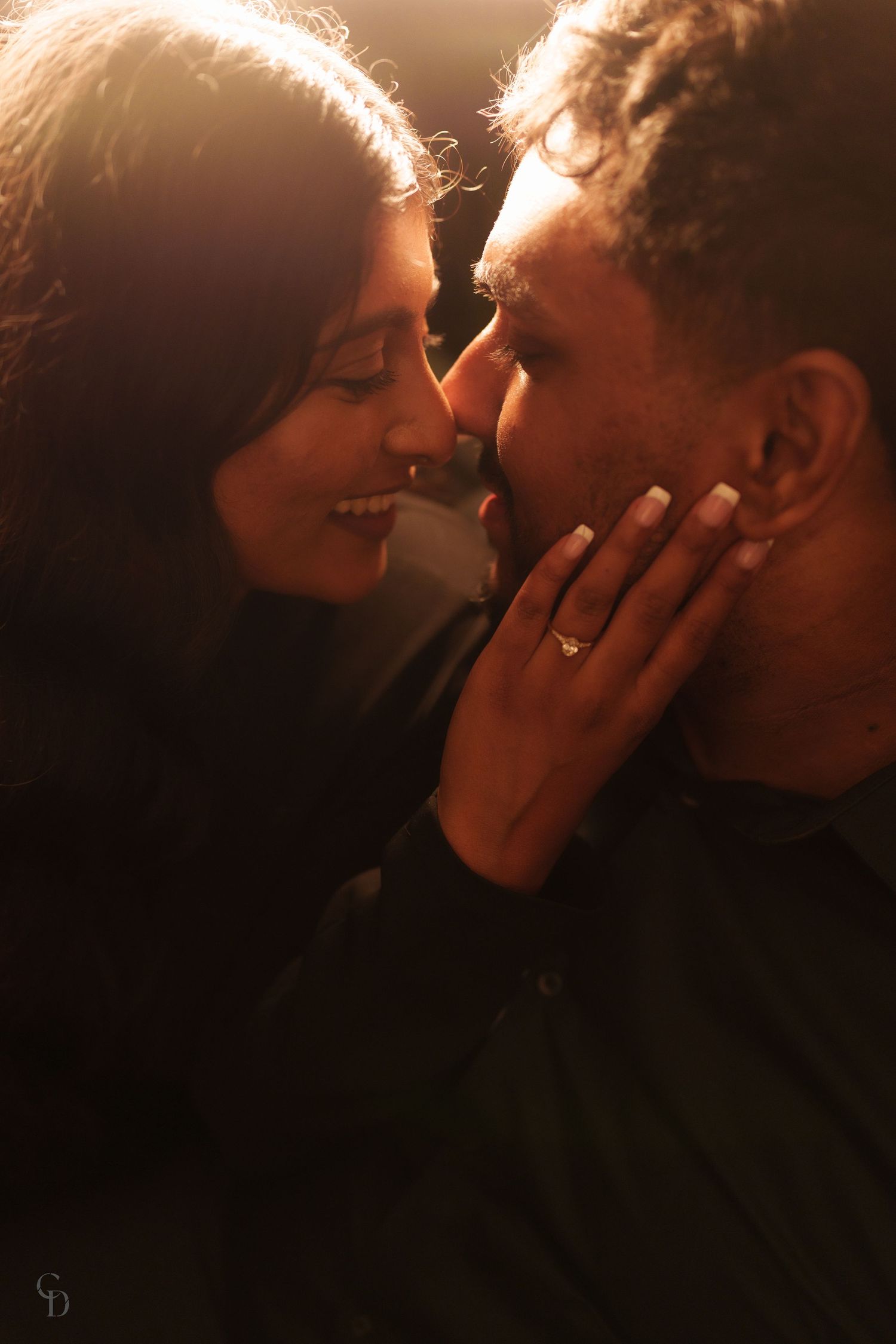 An intimate sunlit portrait captured in golden hour showing a tender moment between a couple.