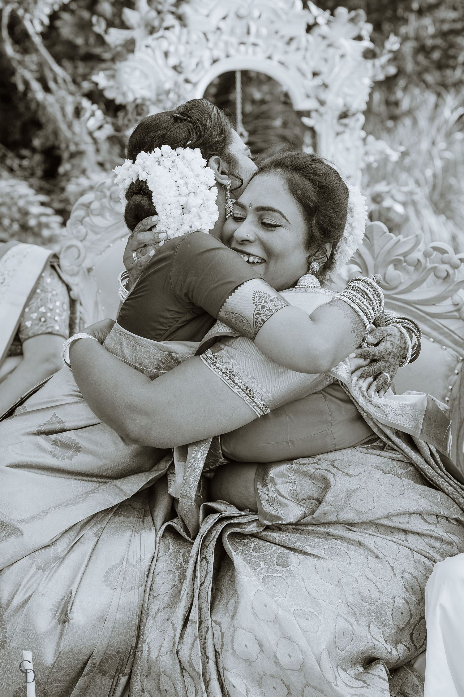 Black and white portrait of two people embracing in traditional South Indian wedding attire.