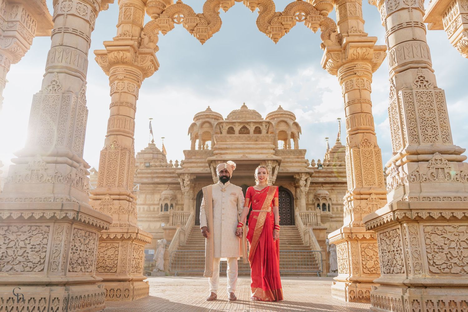 A couple standing under ornate architecture at BAPS Shri Swaminarayan Mandir.