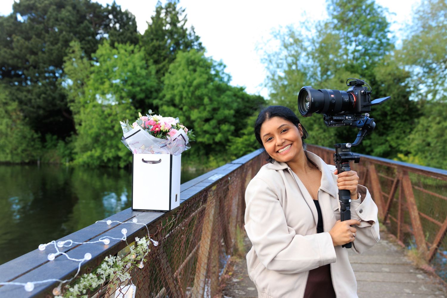 Photographer with camera equipment on wooden bridge over water.
