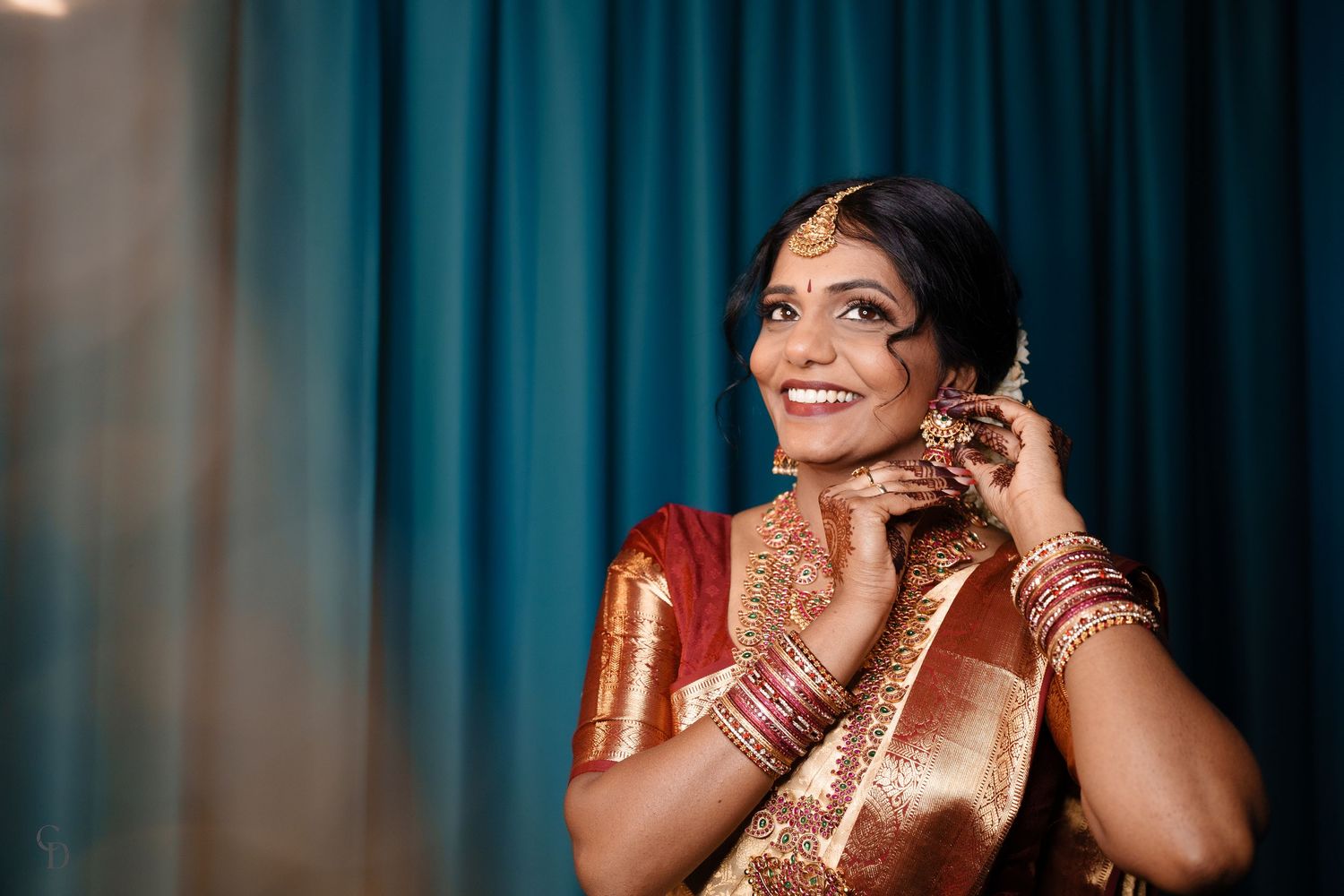 Traditional Indian bride wearing silk saree and jewelry while getting ready.