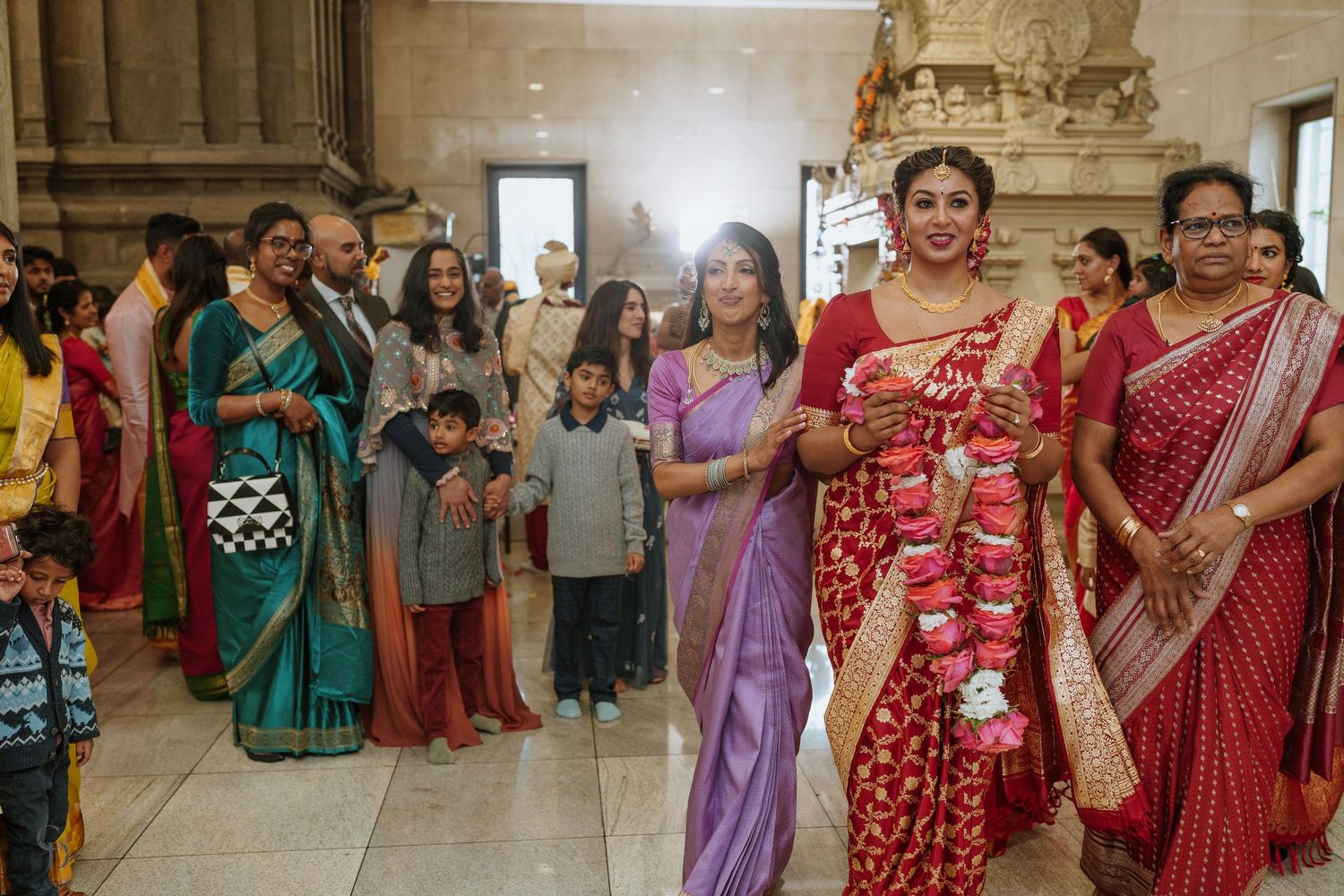 Colorful group gathering in traditional Indian attire inside ornate building.
