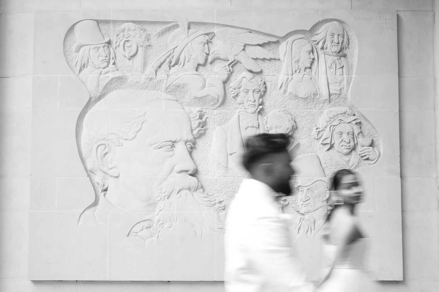 A black and white photo of artwork sketches and outlines displayed on a wall.