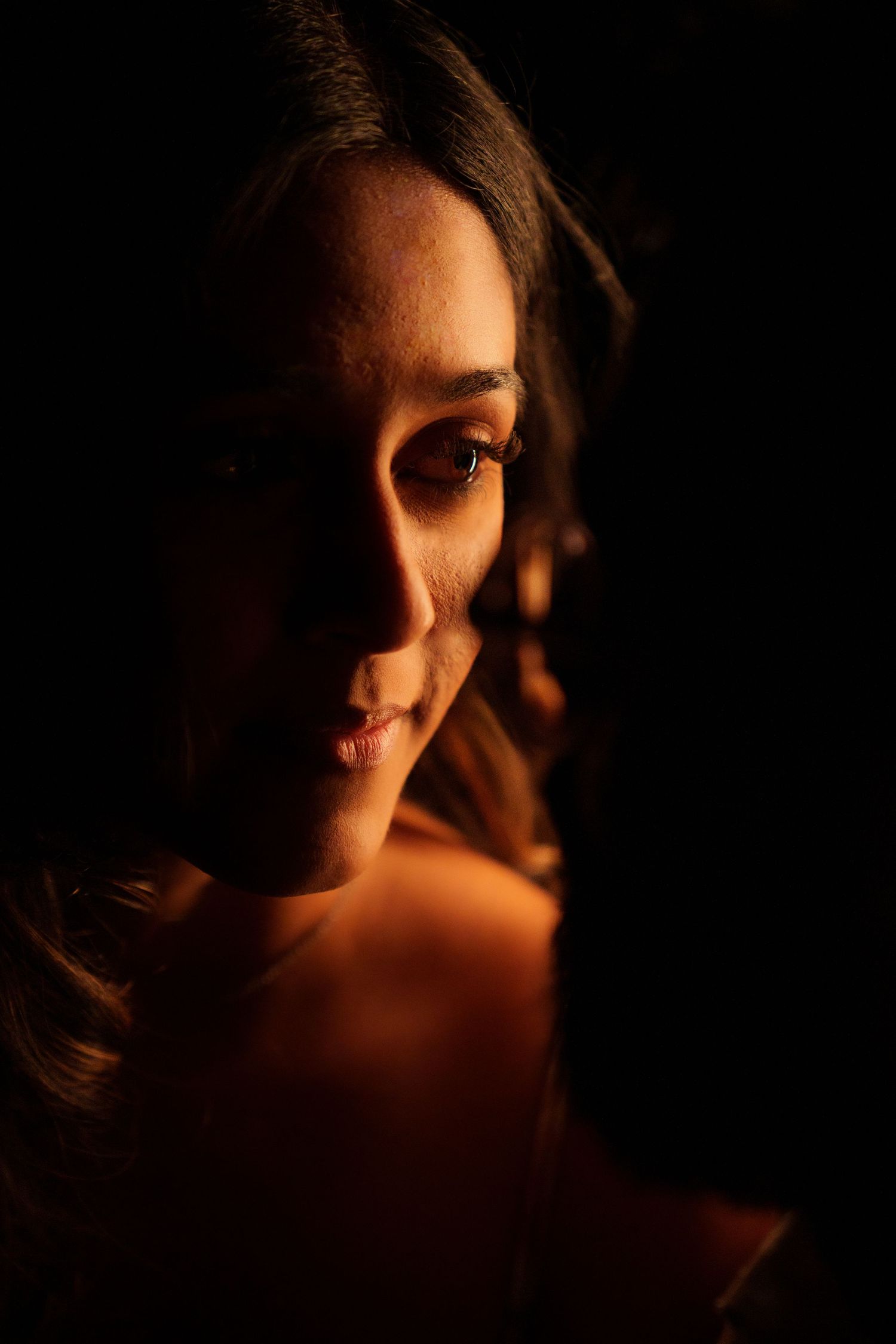 Dramatic side-lit portrait with warm shadows creating moody atmosphere.