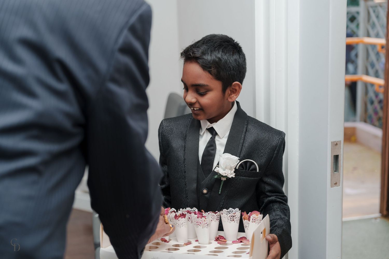 Wedding guest in formal attire serving decorative treats at reception.