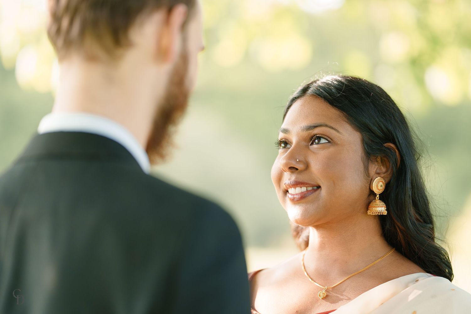 Romantic outdoor portrait capturing loving gaze between couple in elegant attire.