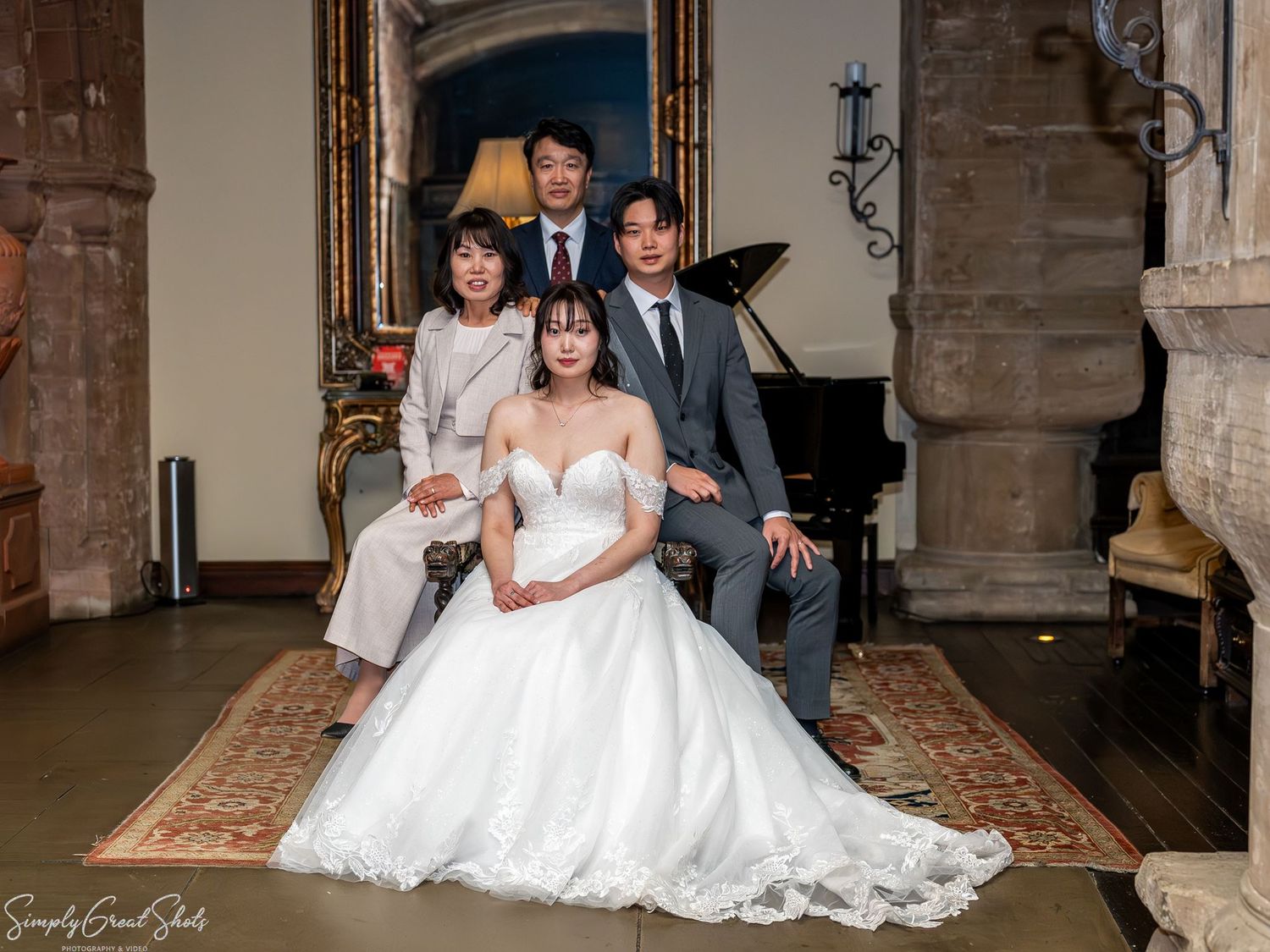 SimplyGreatShots capturing bride Minky and her family posing for a portrait by the piano inside Coombe Abbey.