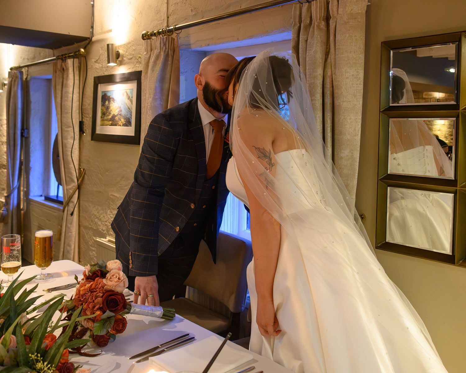 Bride & groom sharing a kiss at the top table during their Saxon Mill wedding breakfast – SimplyGreatShots Photography