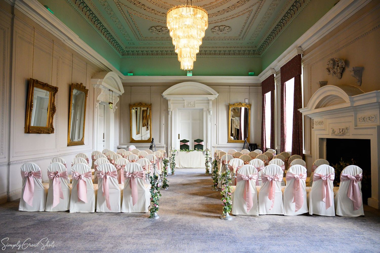 The Cloisters at Coombe Abbey set up for an elegant wedding ceremony with white and pink chair sashes.