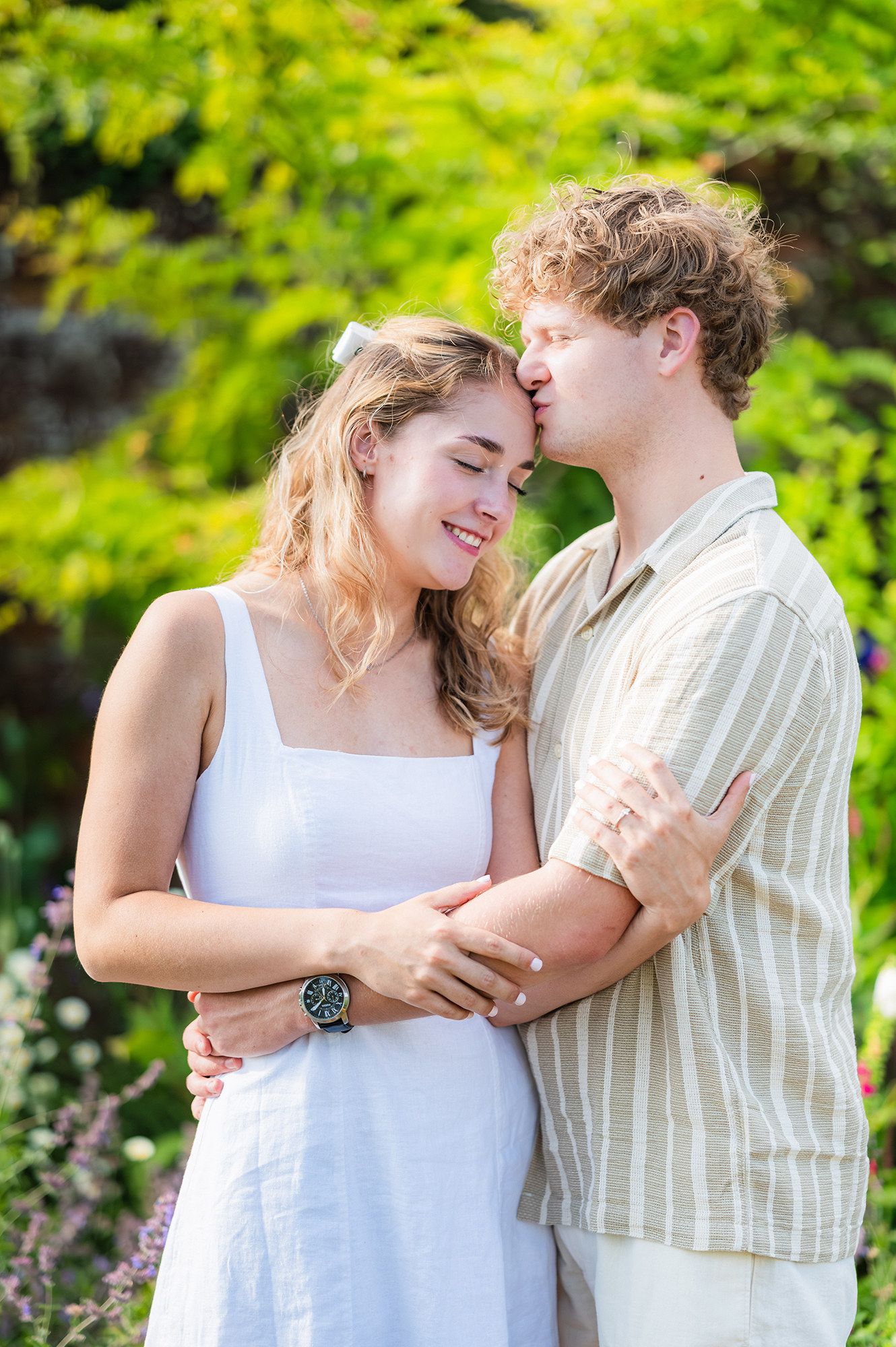 Couple in summer outfits sharing intimate romantic moments in a lush garden setting.