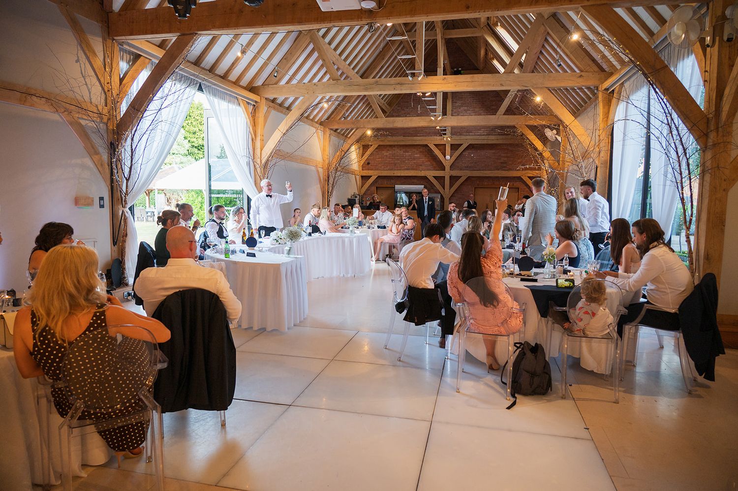 Redhouse Barn wedding photographer capturing reception in rustic barn with exposed beams and elegant decor