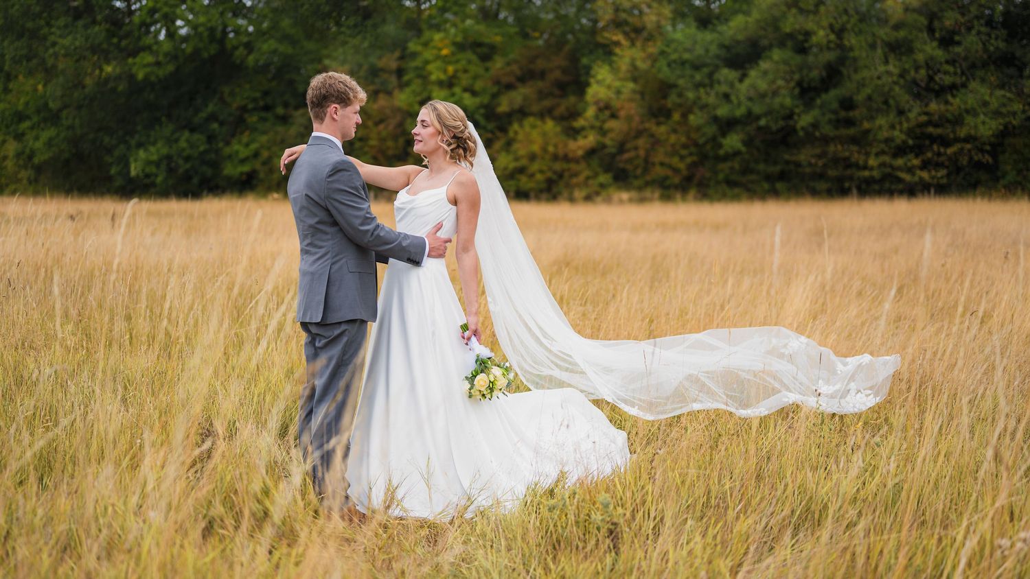 A happy couple spins playfully in a golden wheat field during a romantic photo shoot at sunset on their wedding day.