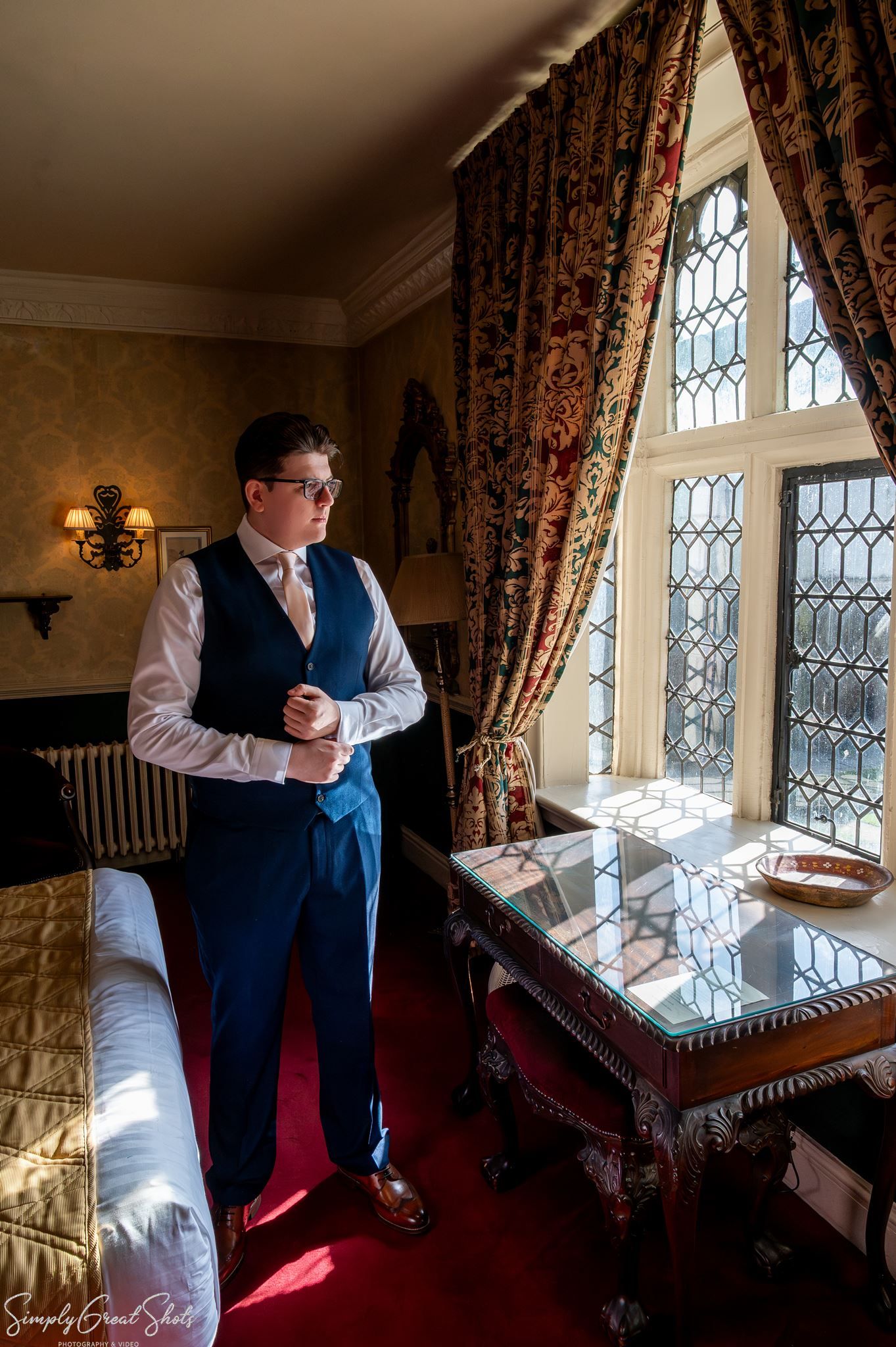 SimplyGreatShots capturing groom Mark adjusting his cuff in a Grand Feature Bedchamber at Coombe Abbey.