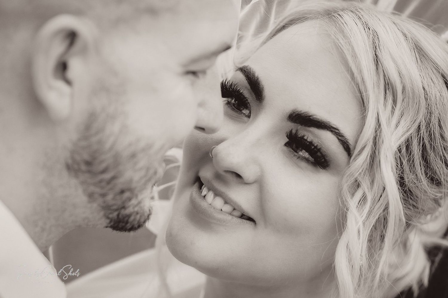 A black-and-white photo of a married couple sharing romantic moment on their wedding day
