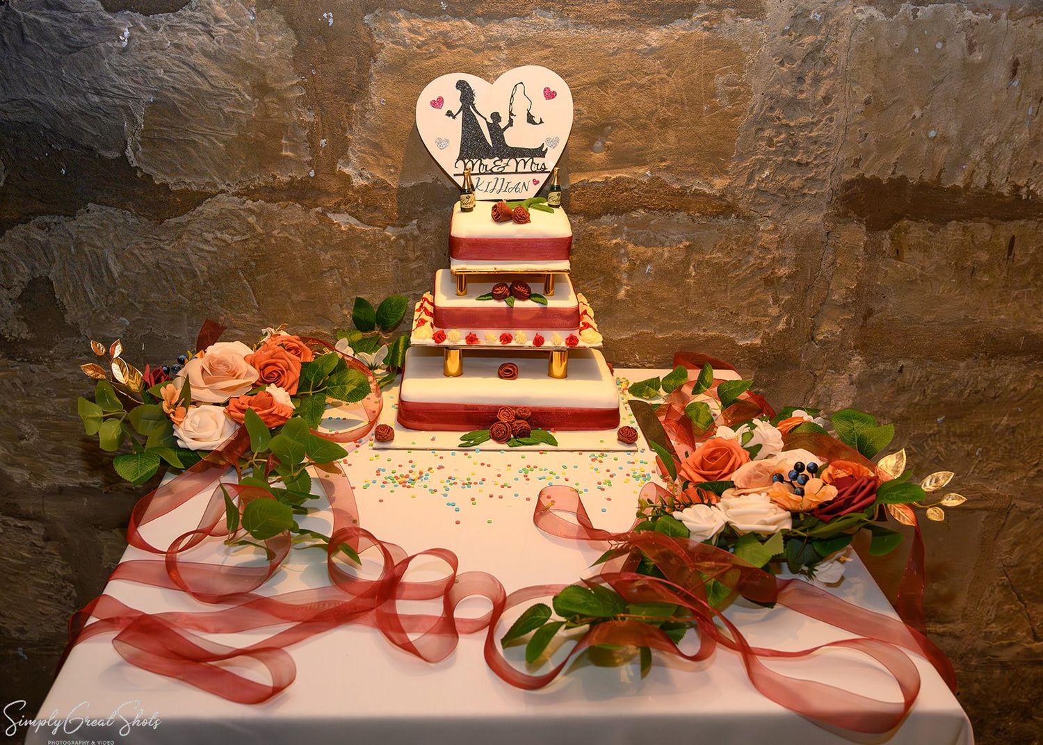 Elegant three-tier wedding cake with red roses & custom topper at Saxon Mill, Warwickshire – SimplyGreatShots Photography