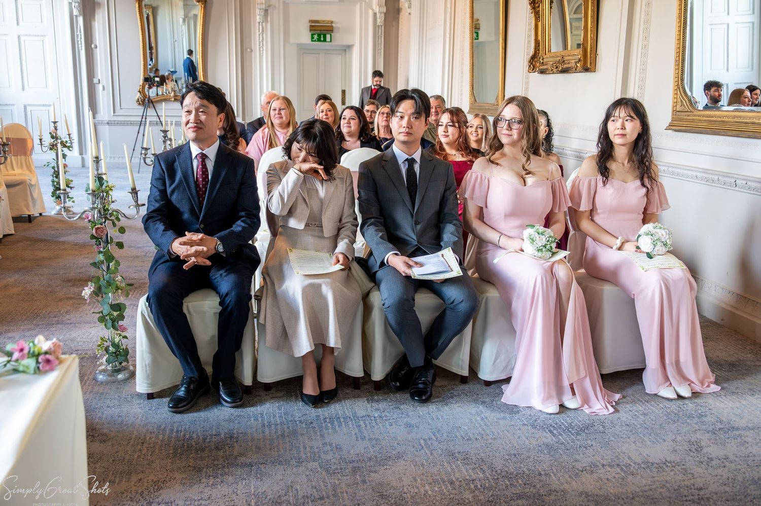 SimplyGreatShots capturing Minky's emotional South Korean family and bridesmaids seated during the ceremony in The Cloisters.